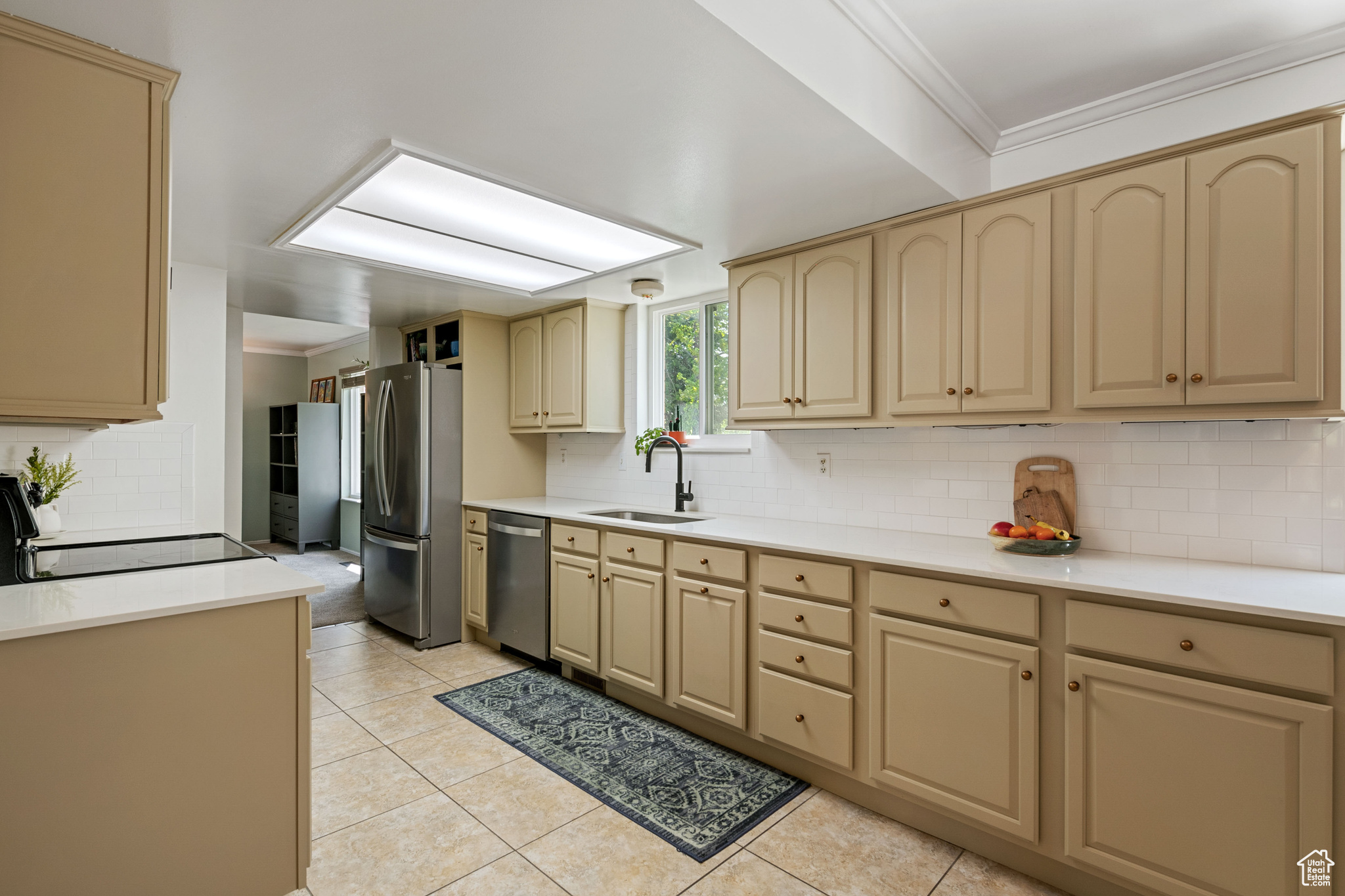 Kitchen featuring crown molding, appliances with stainless steel finishes, sink, light tile floors, and tasteful backsplash