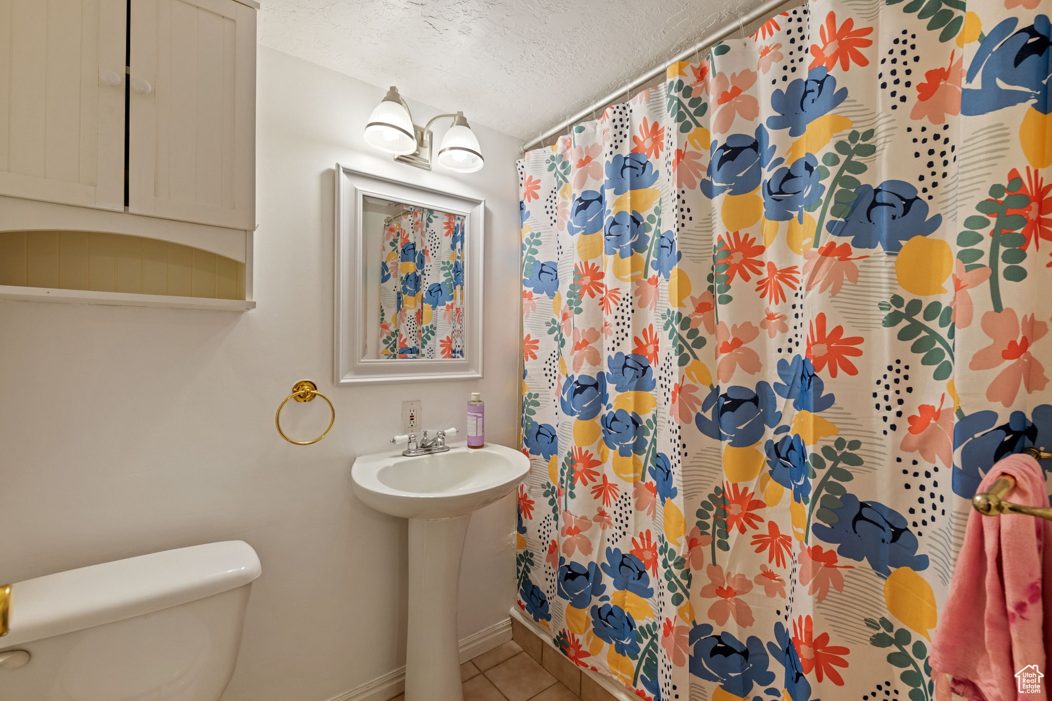 Bathroom featuring toilet, tile floors, and a textured ceiling