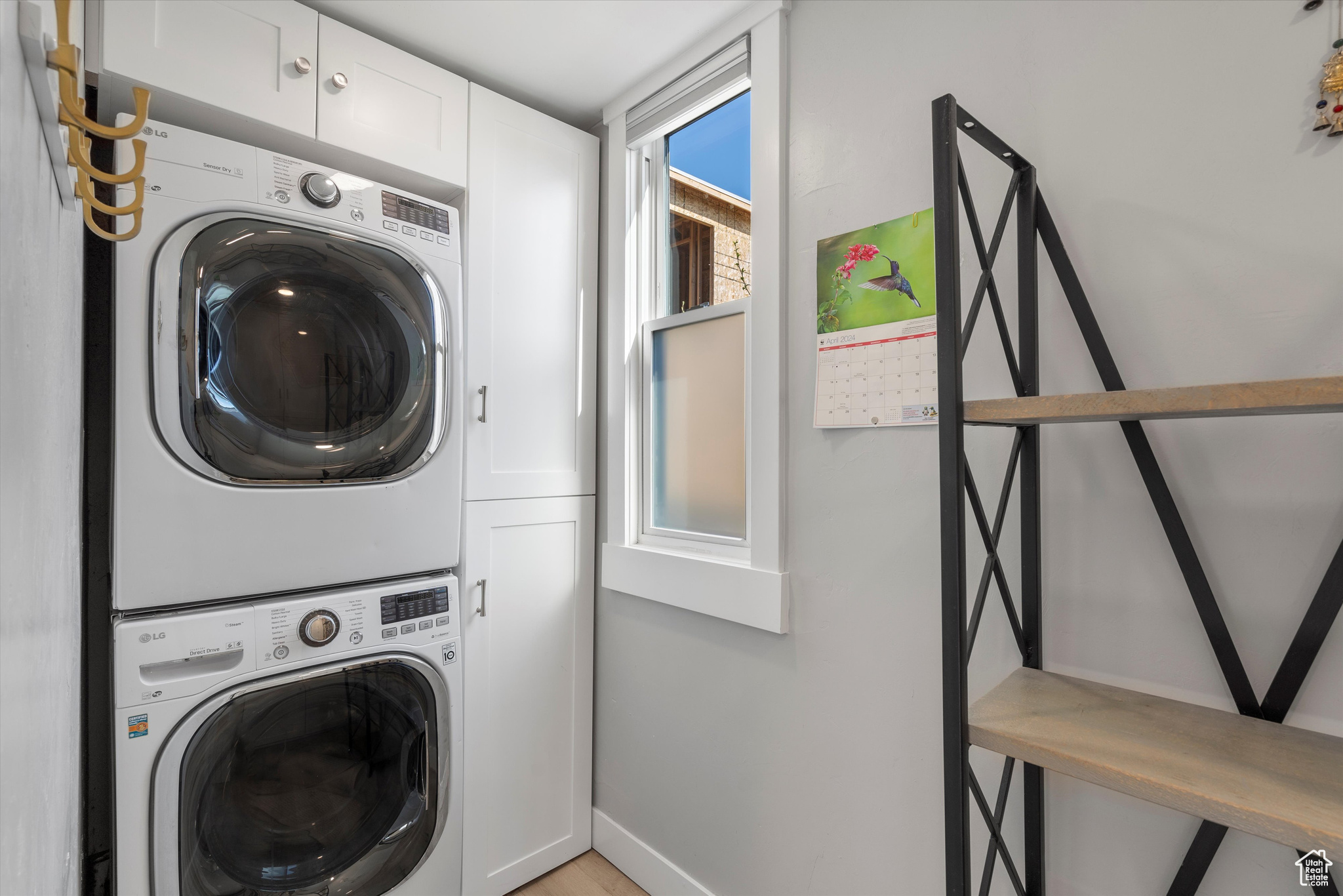 Clothes washing area featuring cabinets and stacked washing maching and dryer