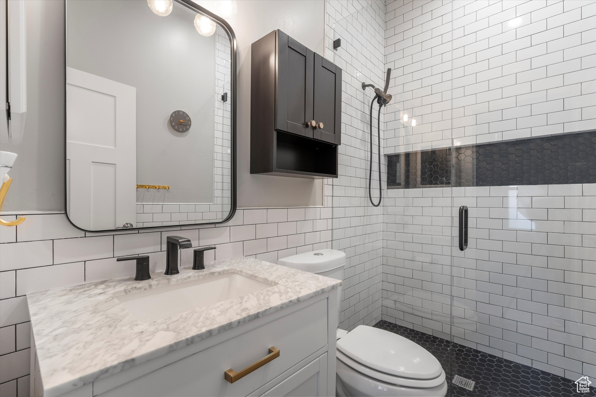 Bathroom featuring tiled shower, tile walls, large vanity