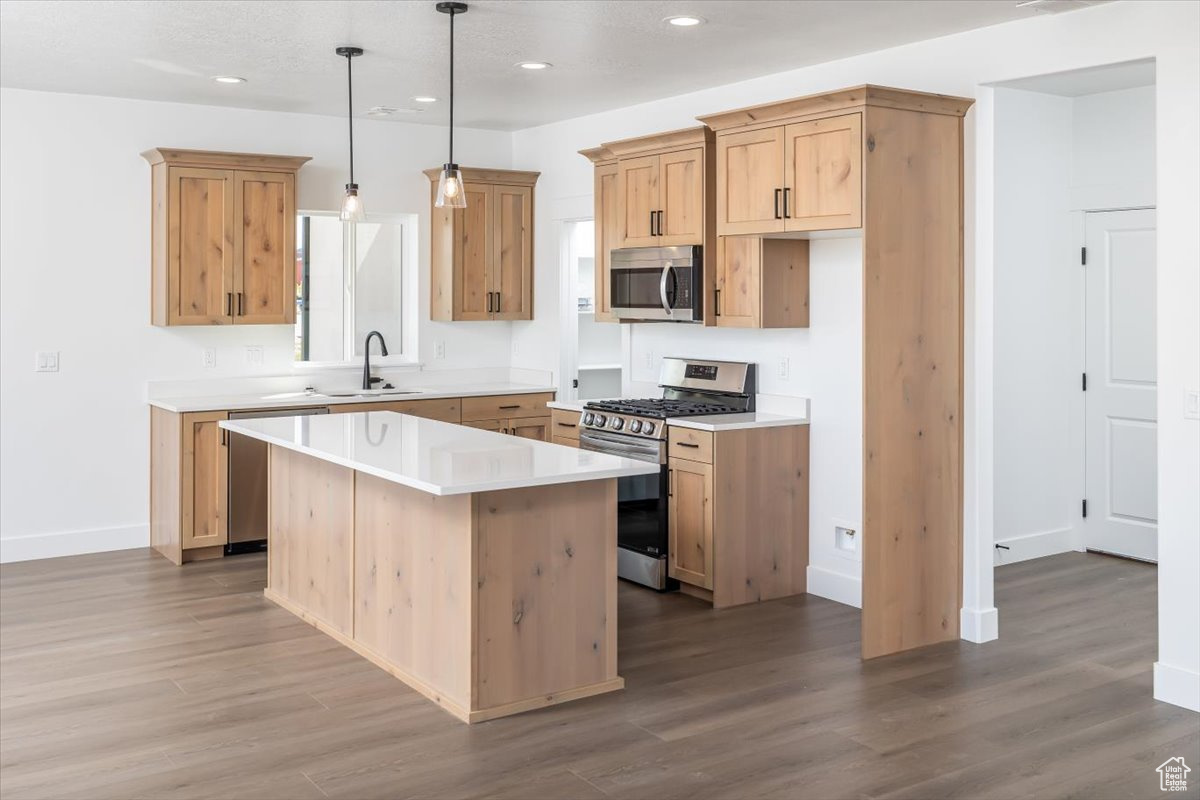 Kitchen featuring a center island, appliances with stainless steel finishes, sink, and hardwood / wood-style flooring