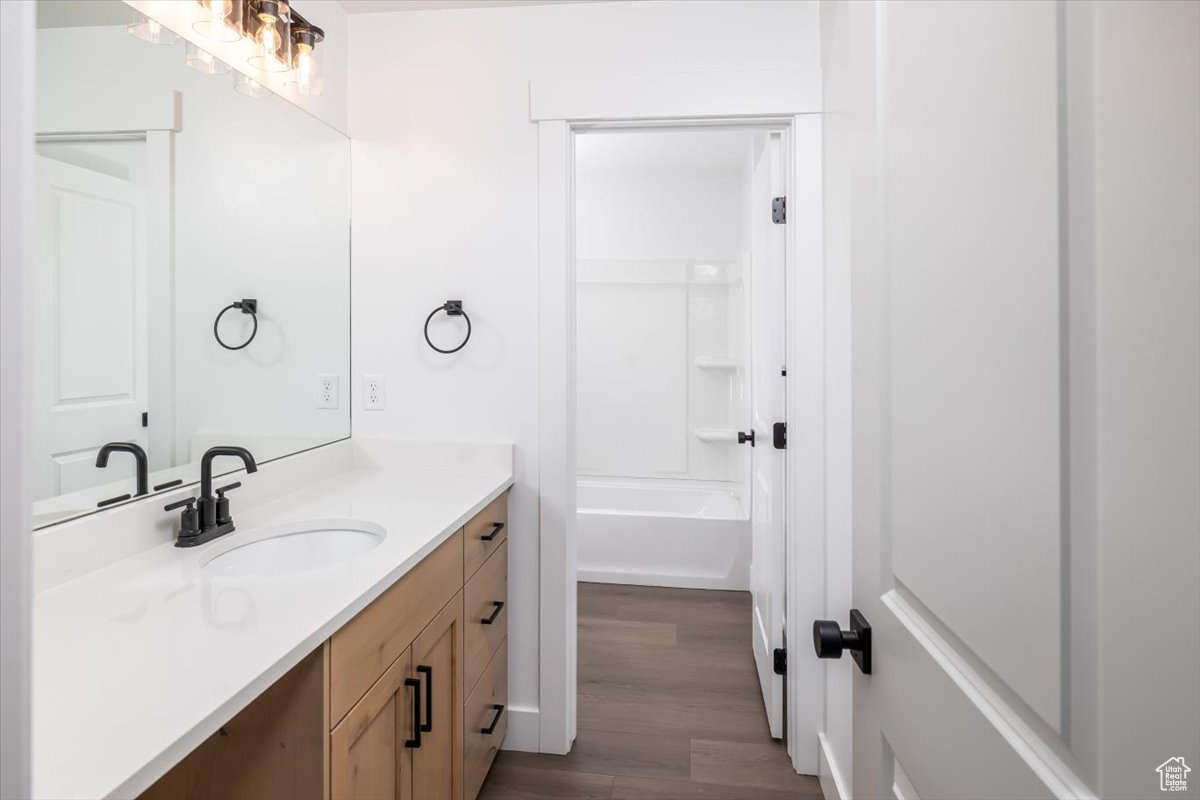 Bathroom featuring hardwood / wood-style flooring, bathtub / shower combination, and vanity with extensive cabinet space