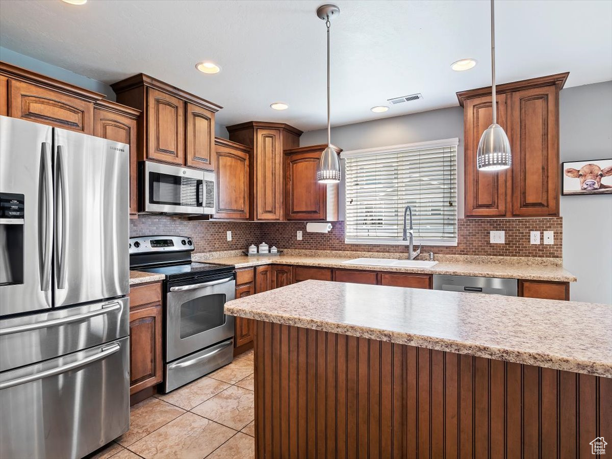 Kitchen with backsplash, pendant lighting, stainless steel appliances, and sink