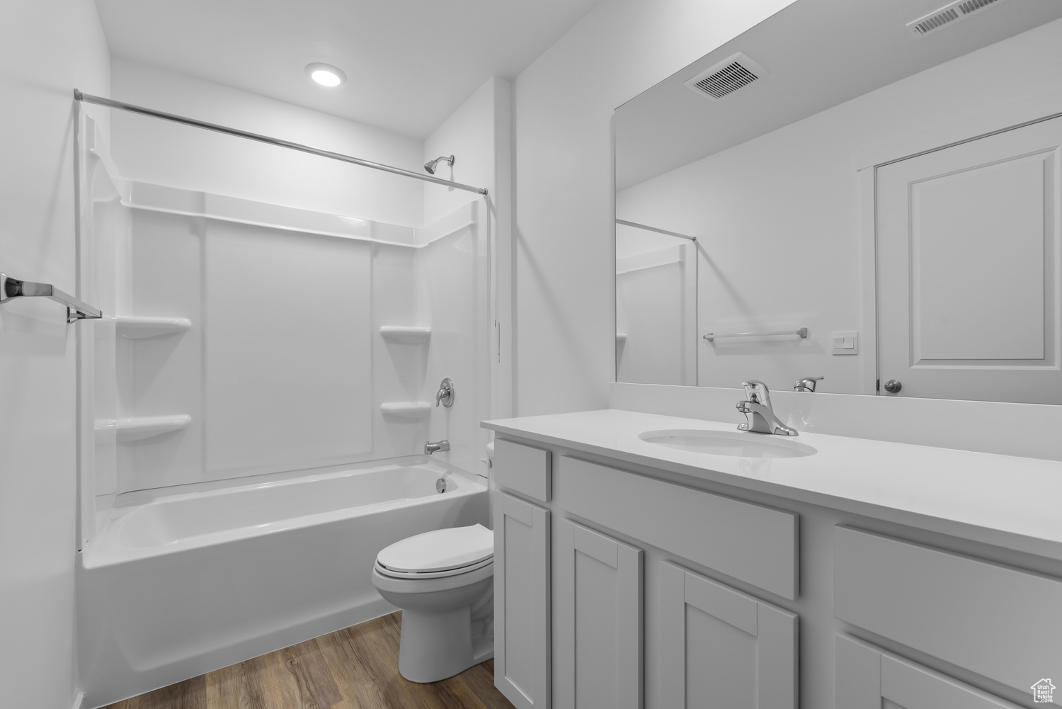 Full bathroom with hardwood / wood-style floors, vanity,  shower combination, and toilet