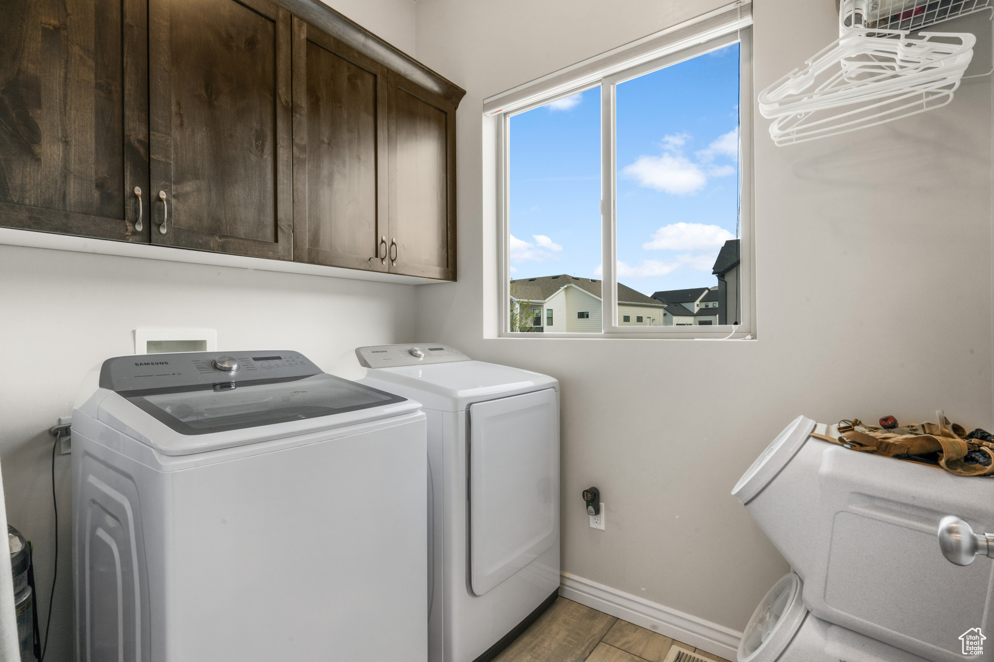 Laundry area featuring a healthy amount of sunlight, cabinets, independent washer and dryer, and light wood-type flooring