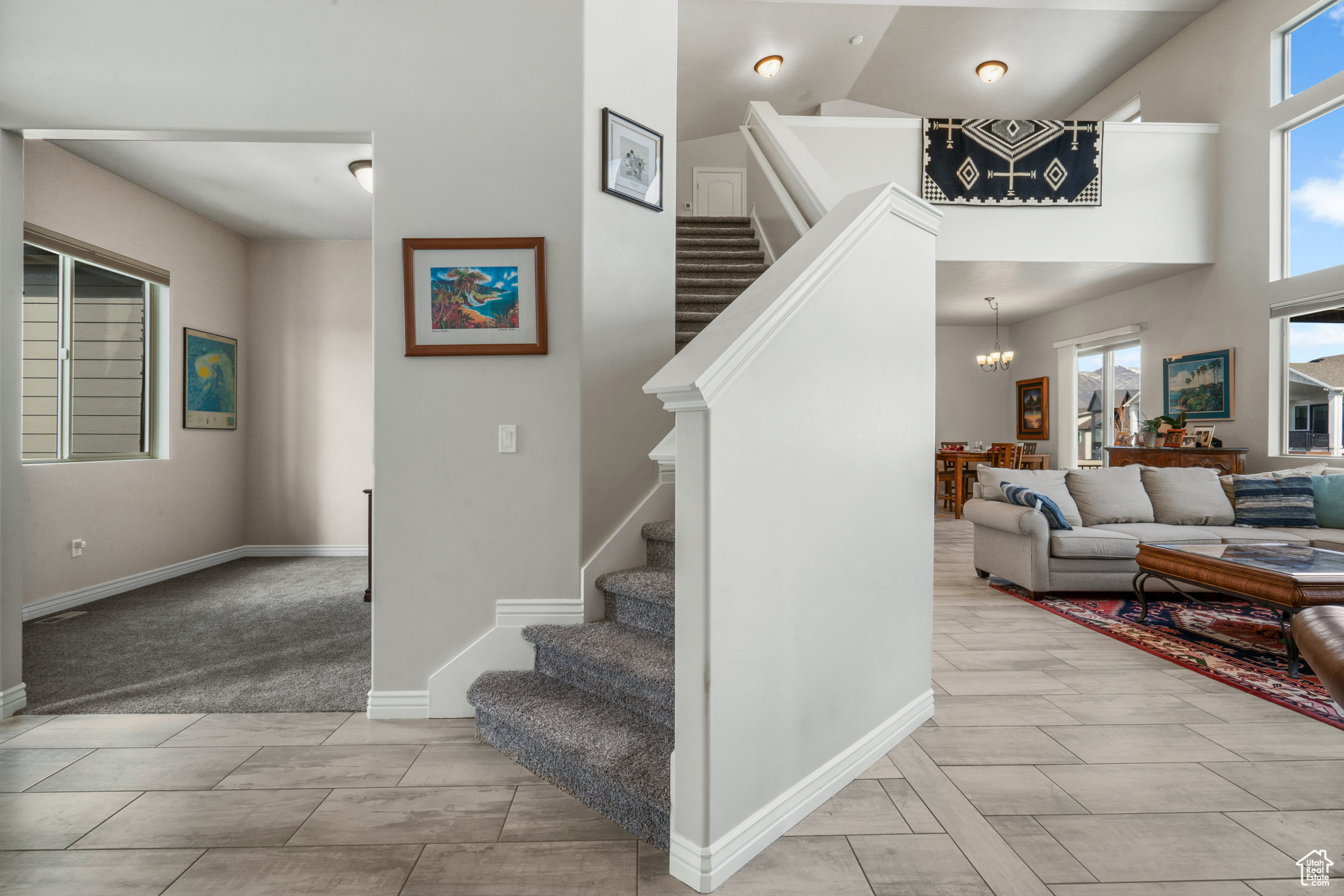 Stairway featuring a notable chandelier, a towering ceiling, and light tile floors