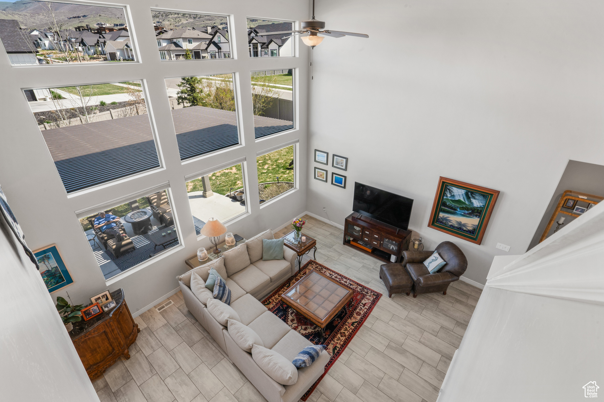 Living room featuring ceiling fan, a high ceiling, and light wood-type flooring