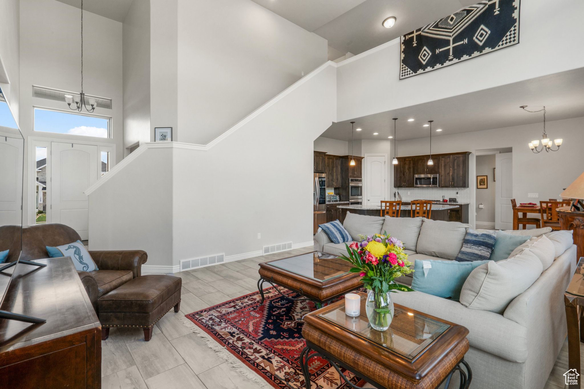 Living room featuring a towering ceiling, light wood-type flooring, and a chandelier