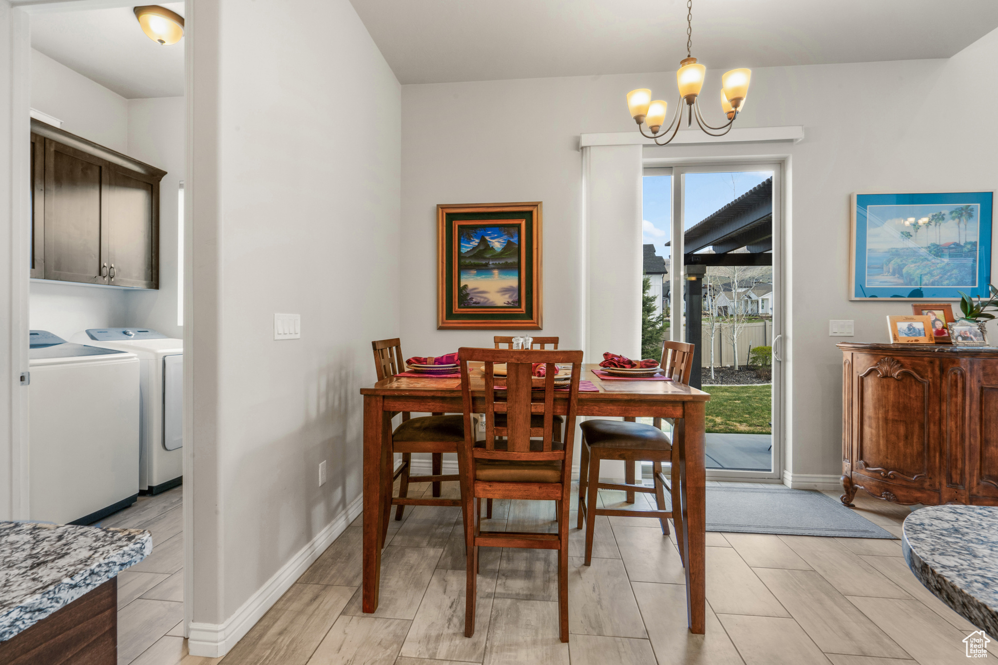 Dining room with a chandelier, washing machine and dryer, and light tile flooring