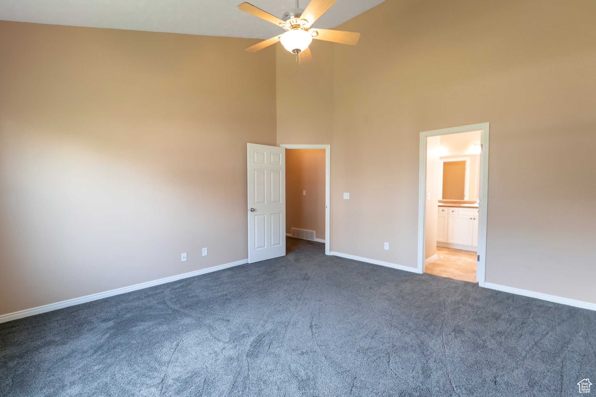 Primary bedroom featuring high vaulted ceiling, connected bathroom, ceiling fan, and carpet floors