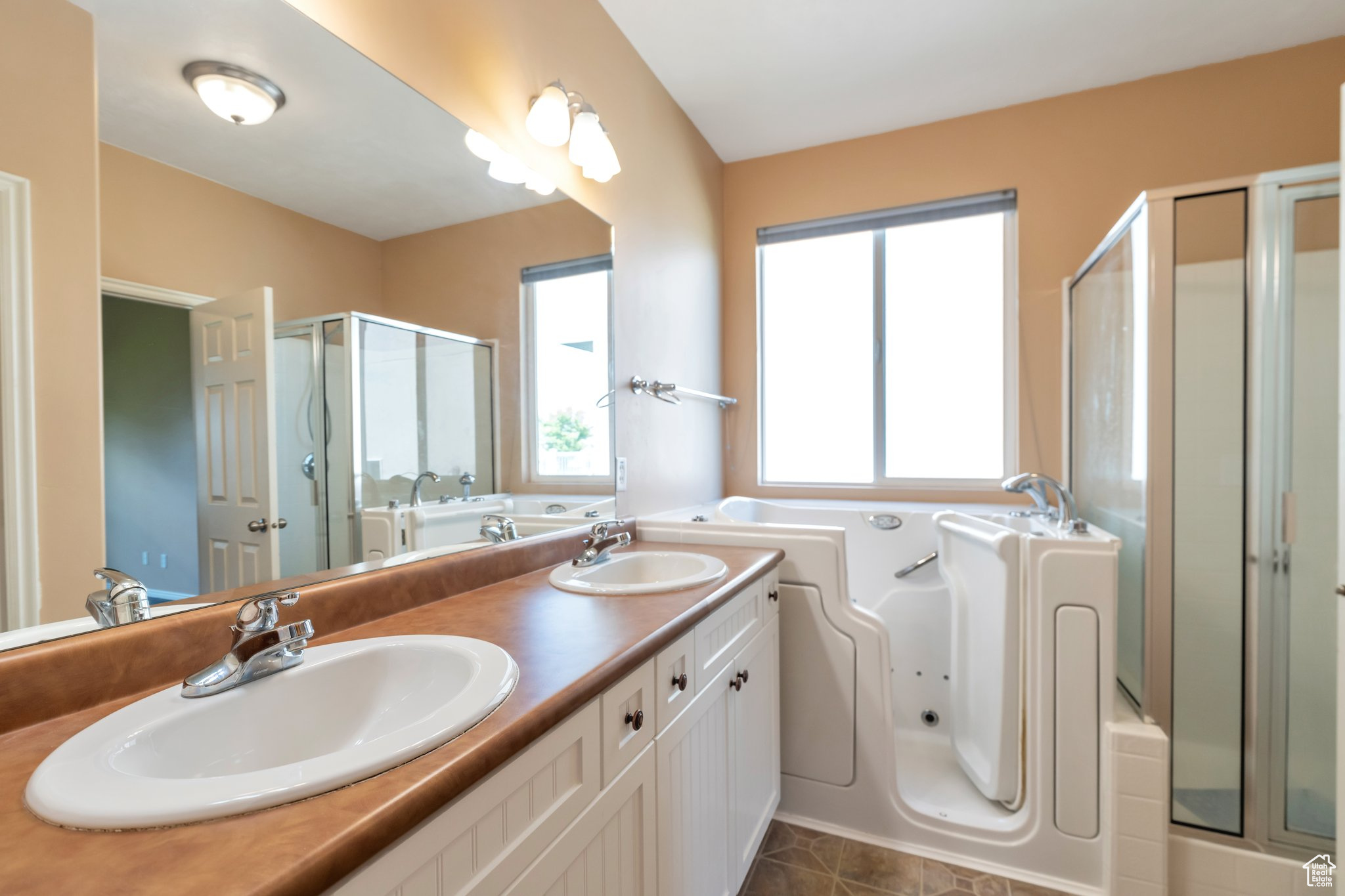 Primary Bathroom featuring tile flooring, dual sinks, oversized vanity, walk in tub and shower