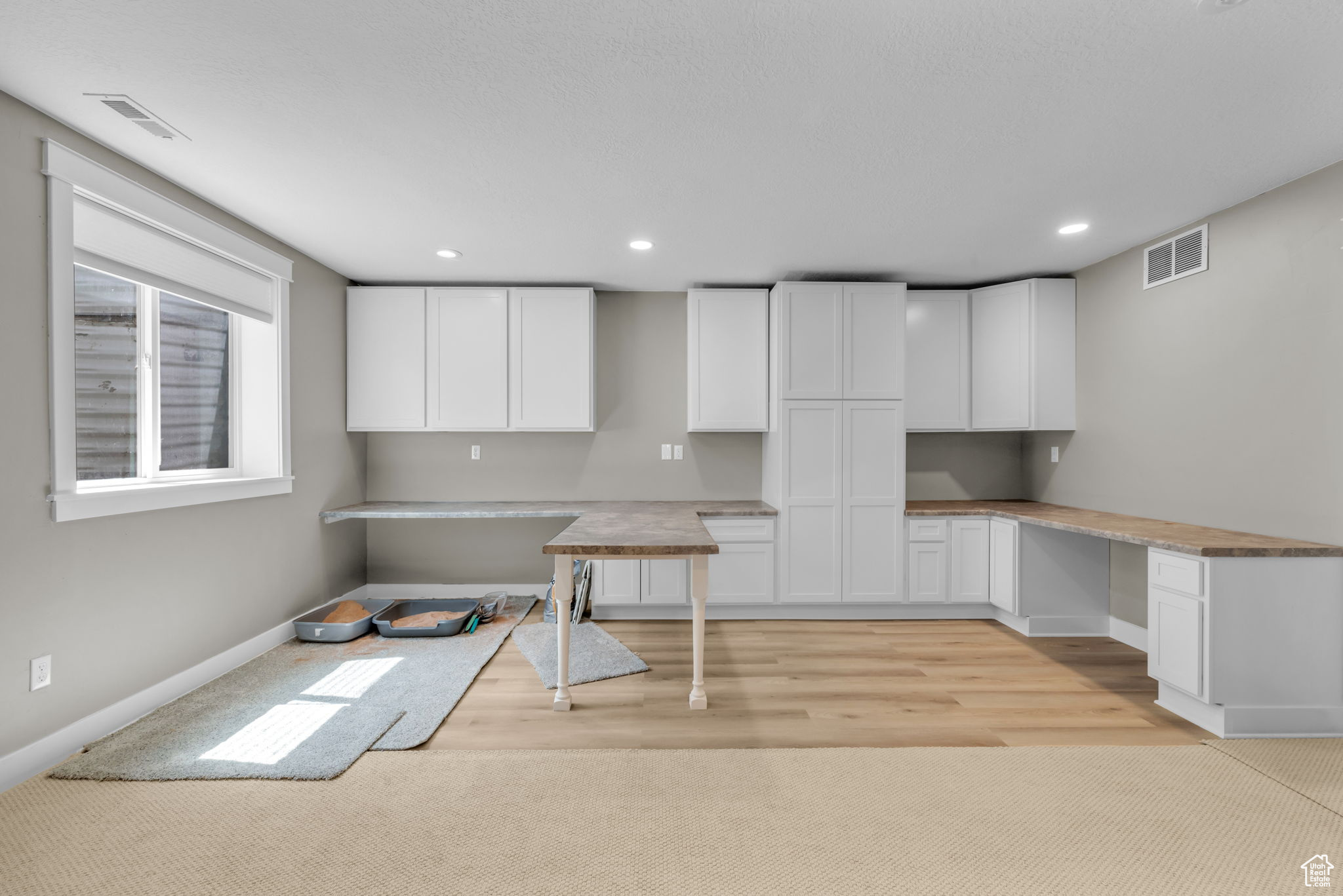 Kitchen with white cabinets, built in desk, and light hardwood / wood-style floors