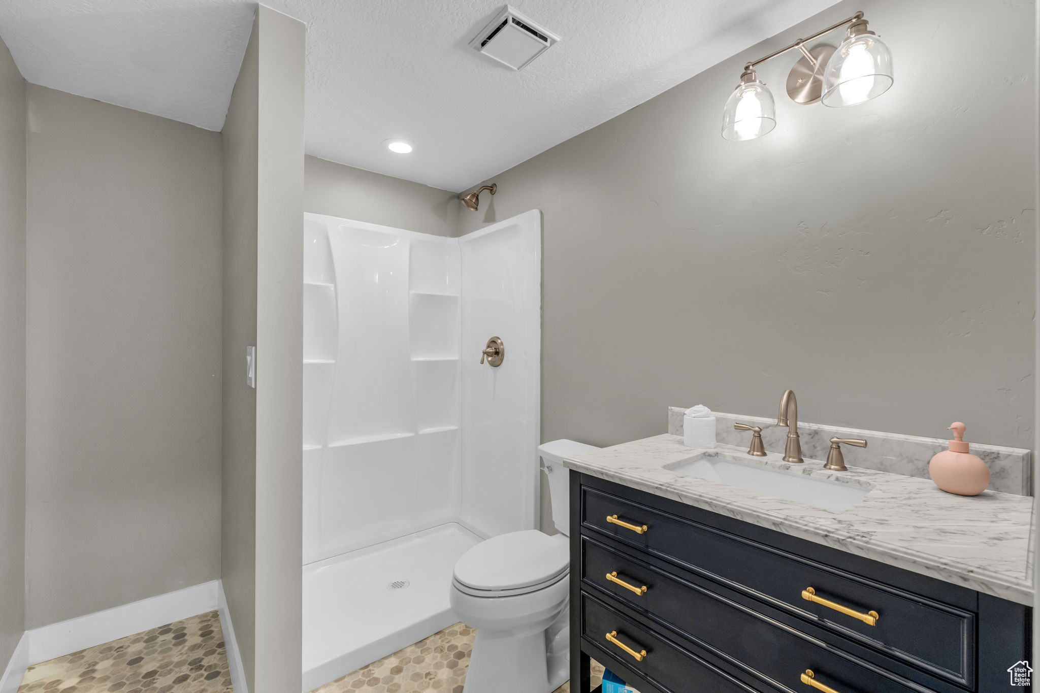 Bathroom featuring a textured ceiling, walk in shower, toilet, tile floors, and vanity
