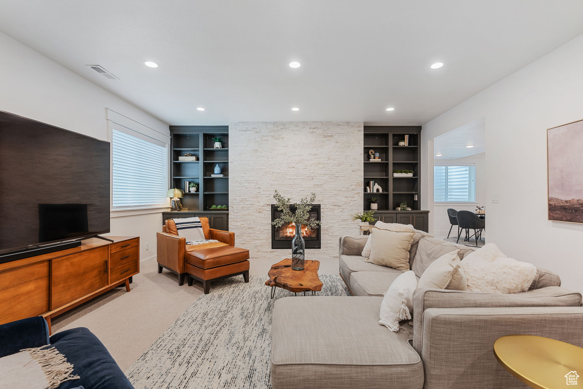 Living room with built in shelves, a 2nd gas fireplace, Hillburn wool carpet and white ledge stone finish feature wall.