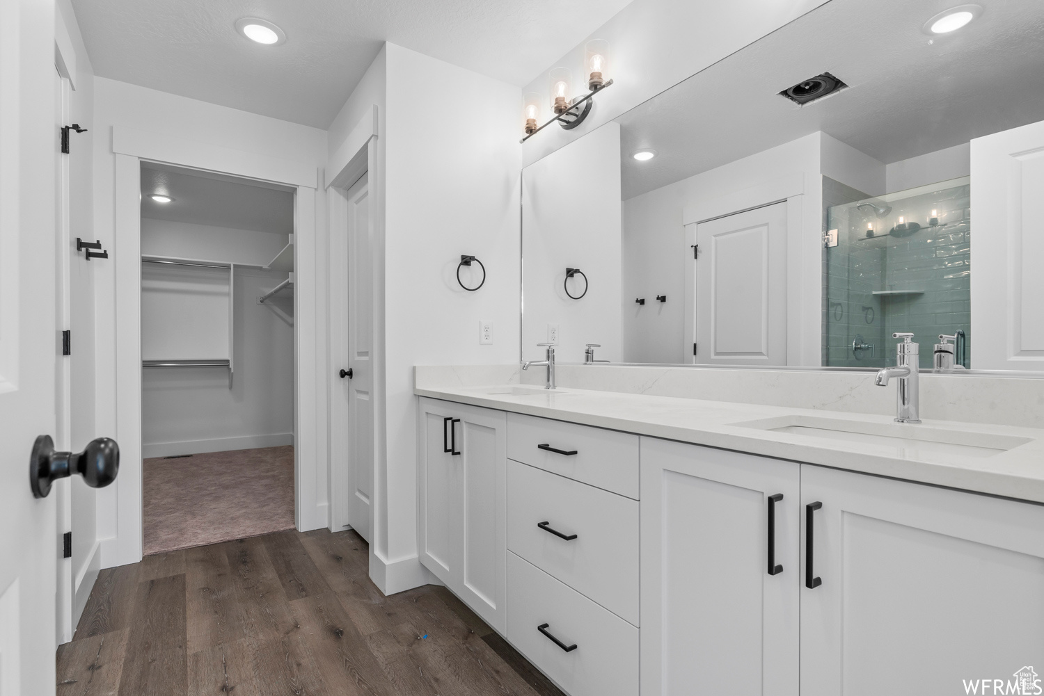 Bathroom with hardwood / wood-style flooring, an enclosed shower, and dual vanity