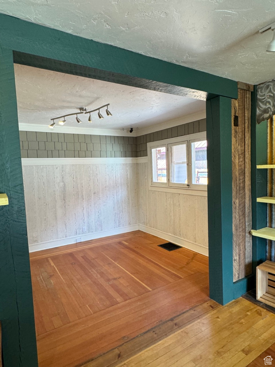 Spare room with wood walls, track lighting, hardwood / wood-style flooring, and a textured ceiling
