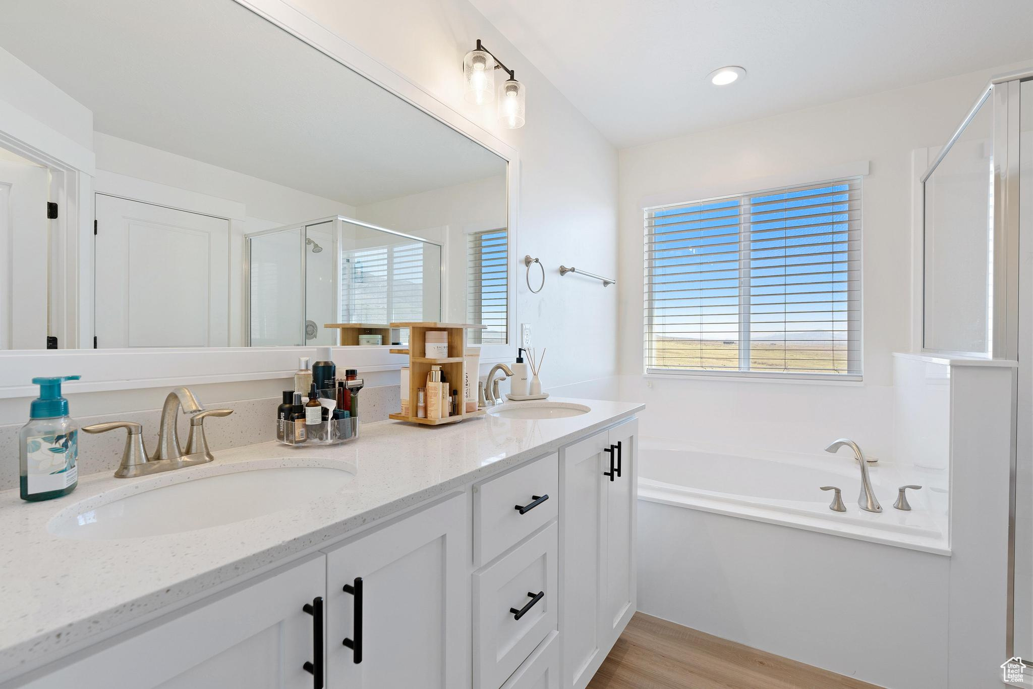 Bathroom with hardwood / wood-style flooring, independent shower and bath, and dual vanity