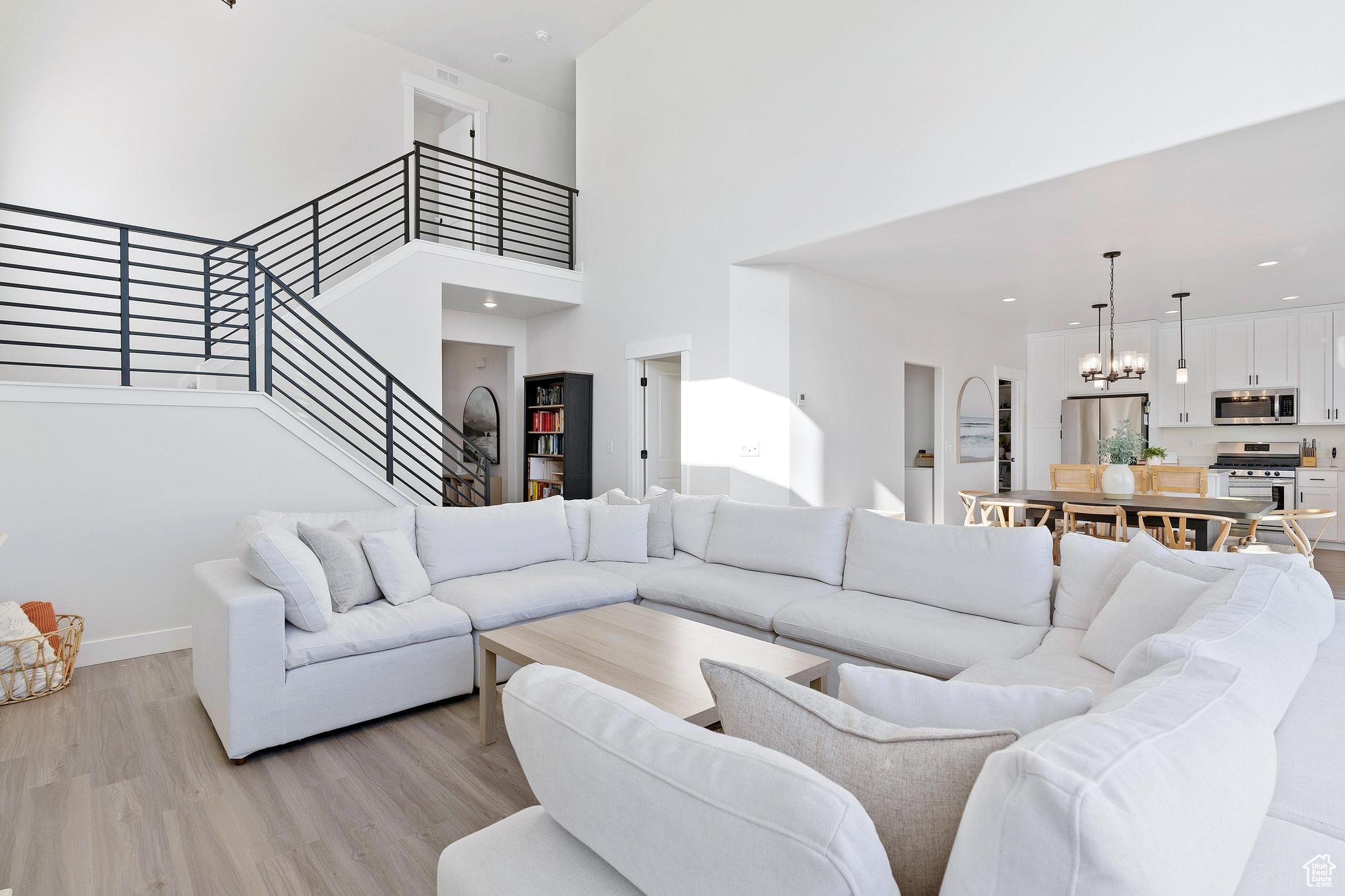 Living room featuring a notable chandelier, light hardwood / wood-style floors, and a high ceiling