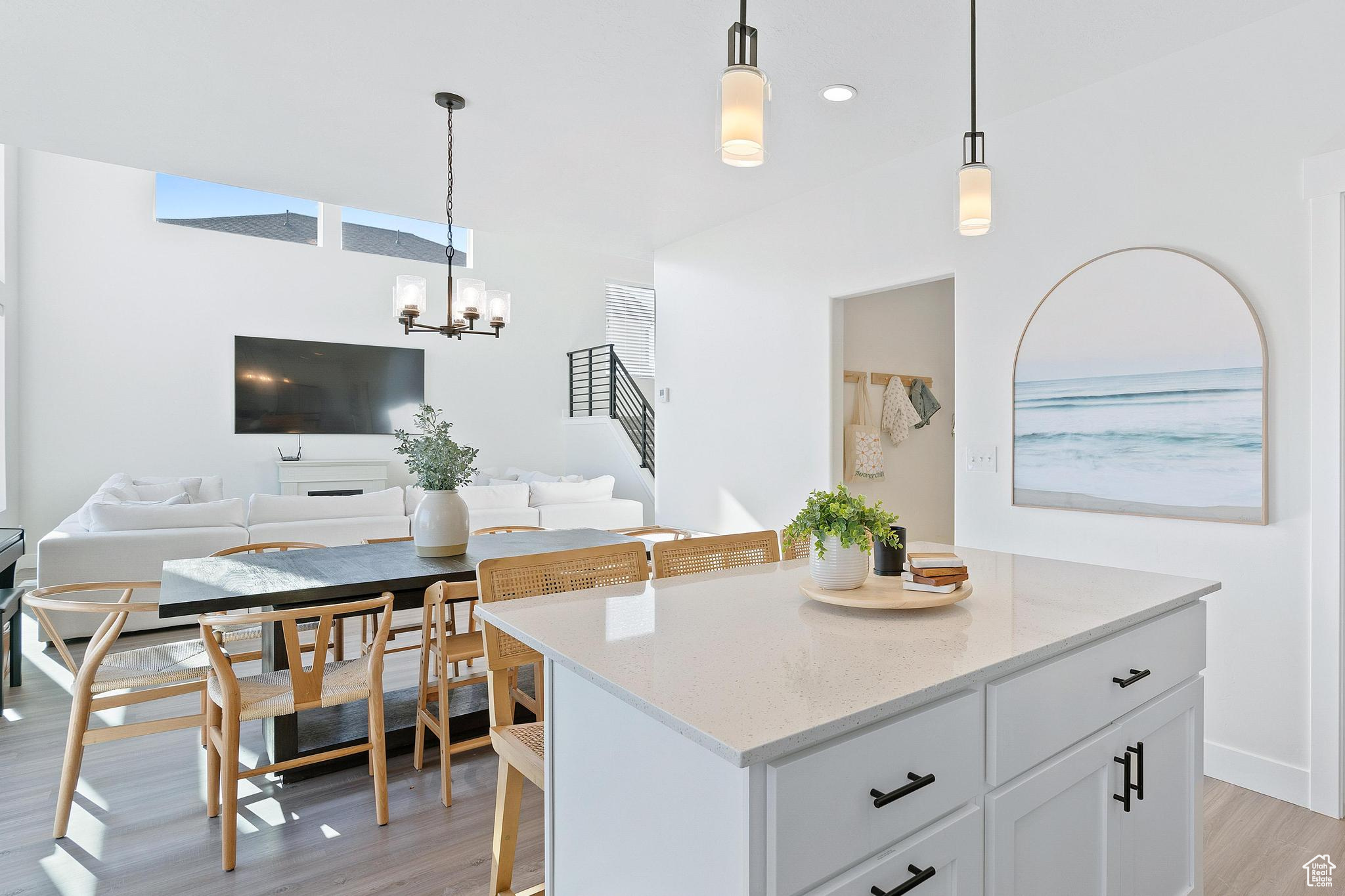 Kitchen featuring a kitchen island, hanging light fixtures, an inviting chandelier, light hardwood / wood-style flooring, and light stone countertops