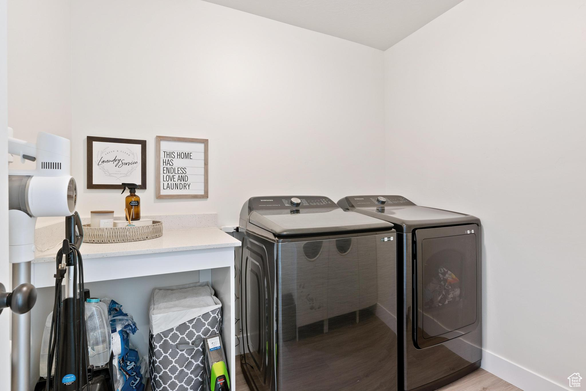 Laundry area featuring washing machine and clothes dryer and light wood-type flooring