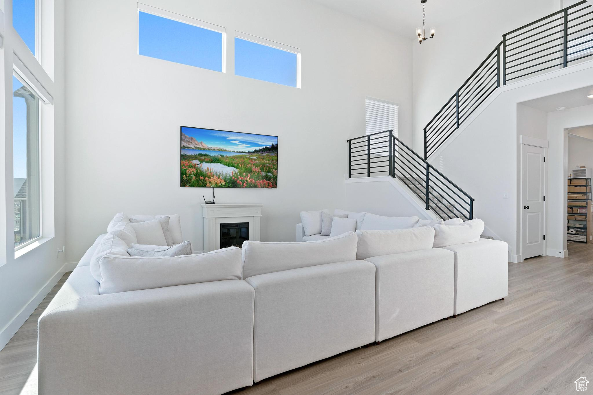 Living room with light hardwood / wood-style flooring and a towering ceiling