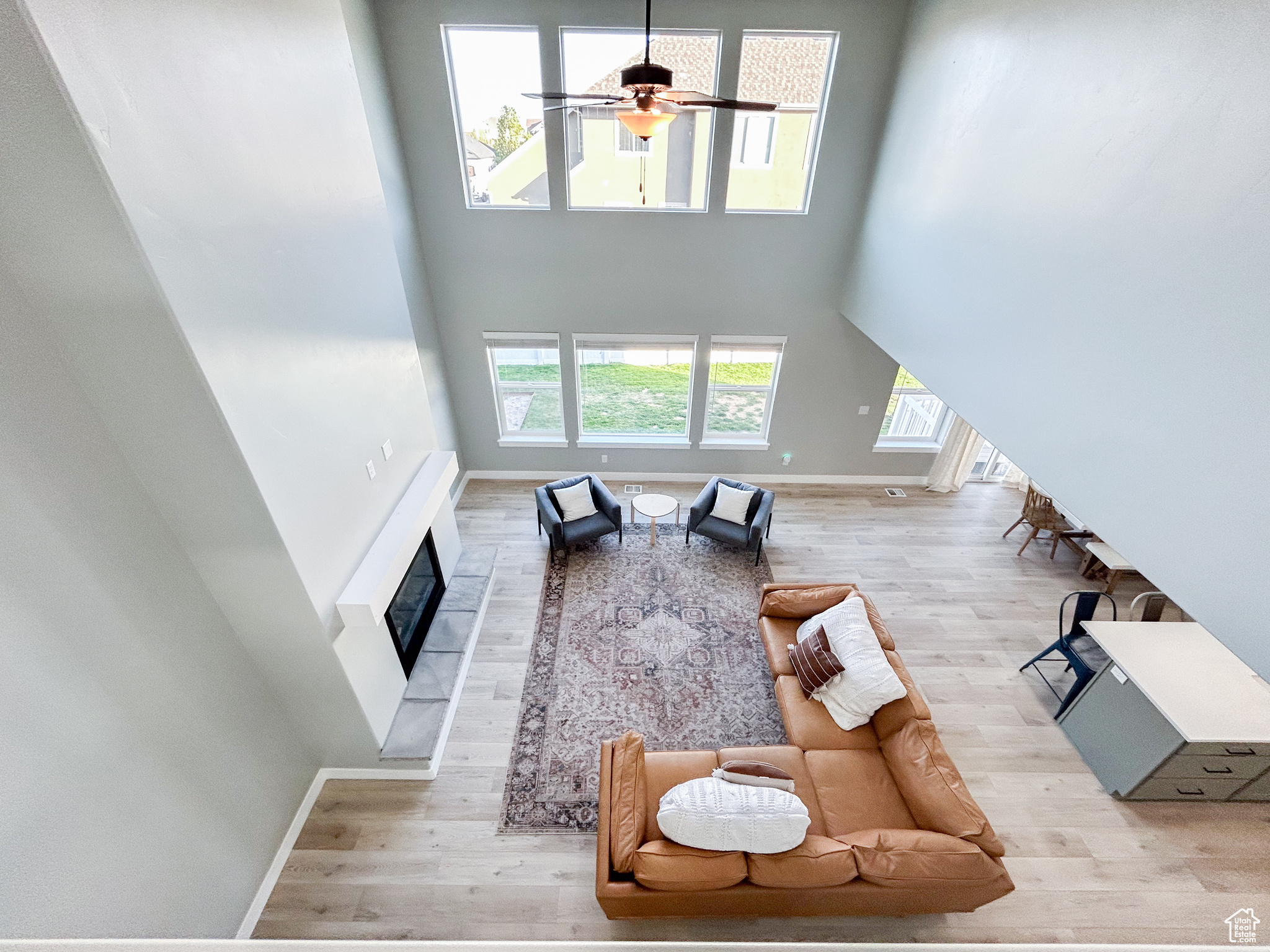 Living room featuring light hardwood / wood-style flooring, ceiling fan, and a towering ceiling