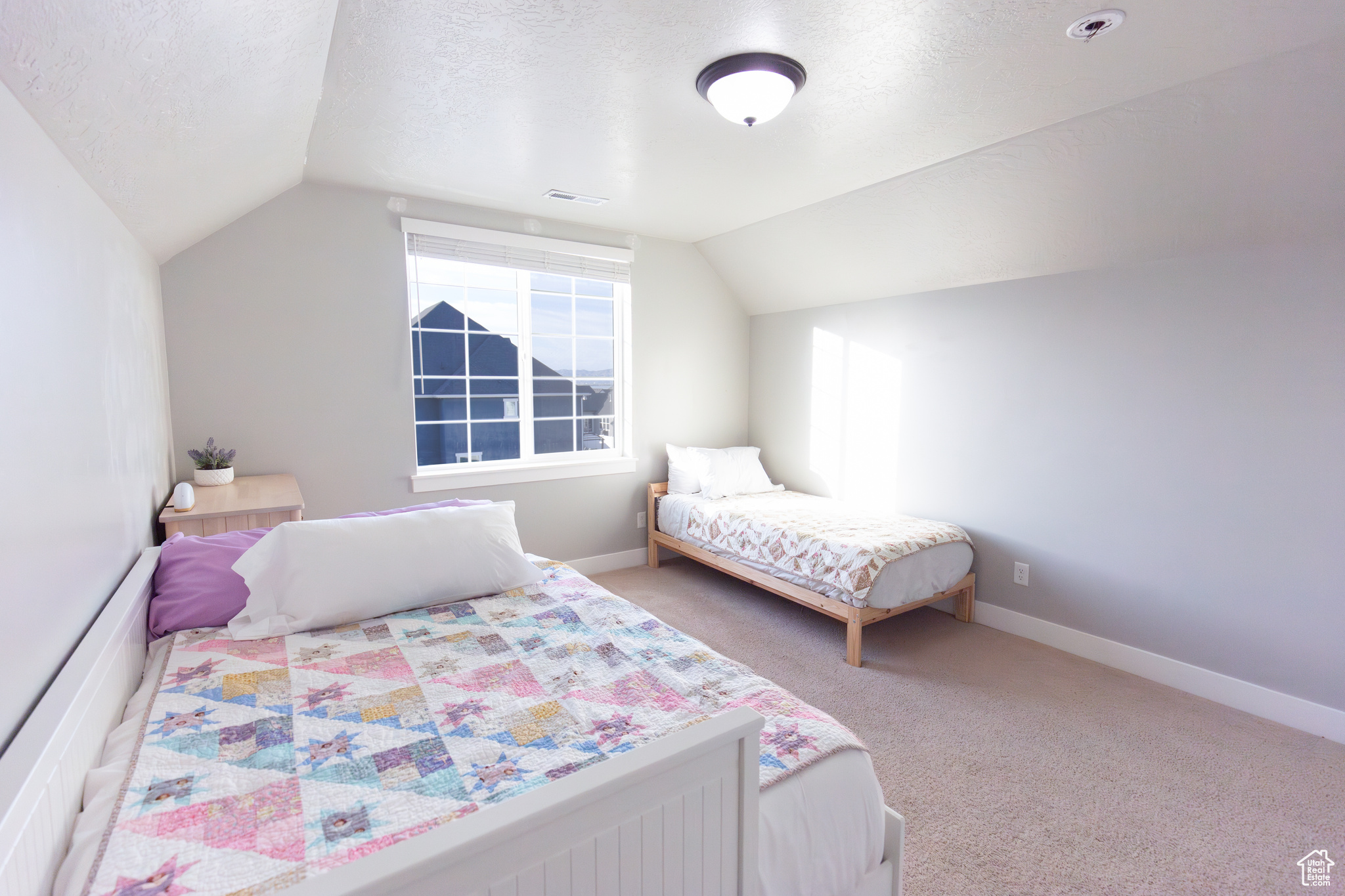 Bedroom featuring vaulted ceiling, carpet floors, and a textured ceiling