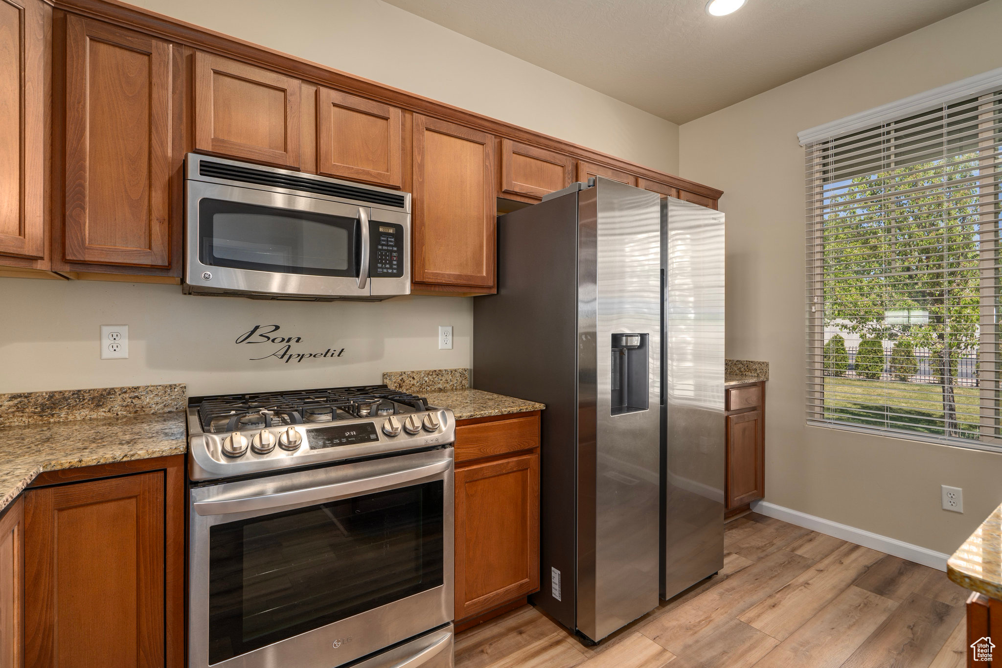 Kitchen featuring light hardwood / wood-style floors, appliances with stainless steel finishes, and light stone countertops