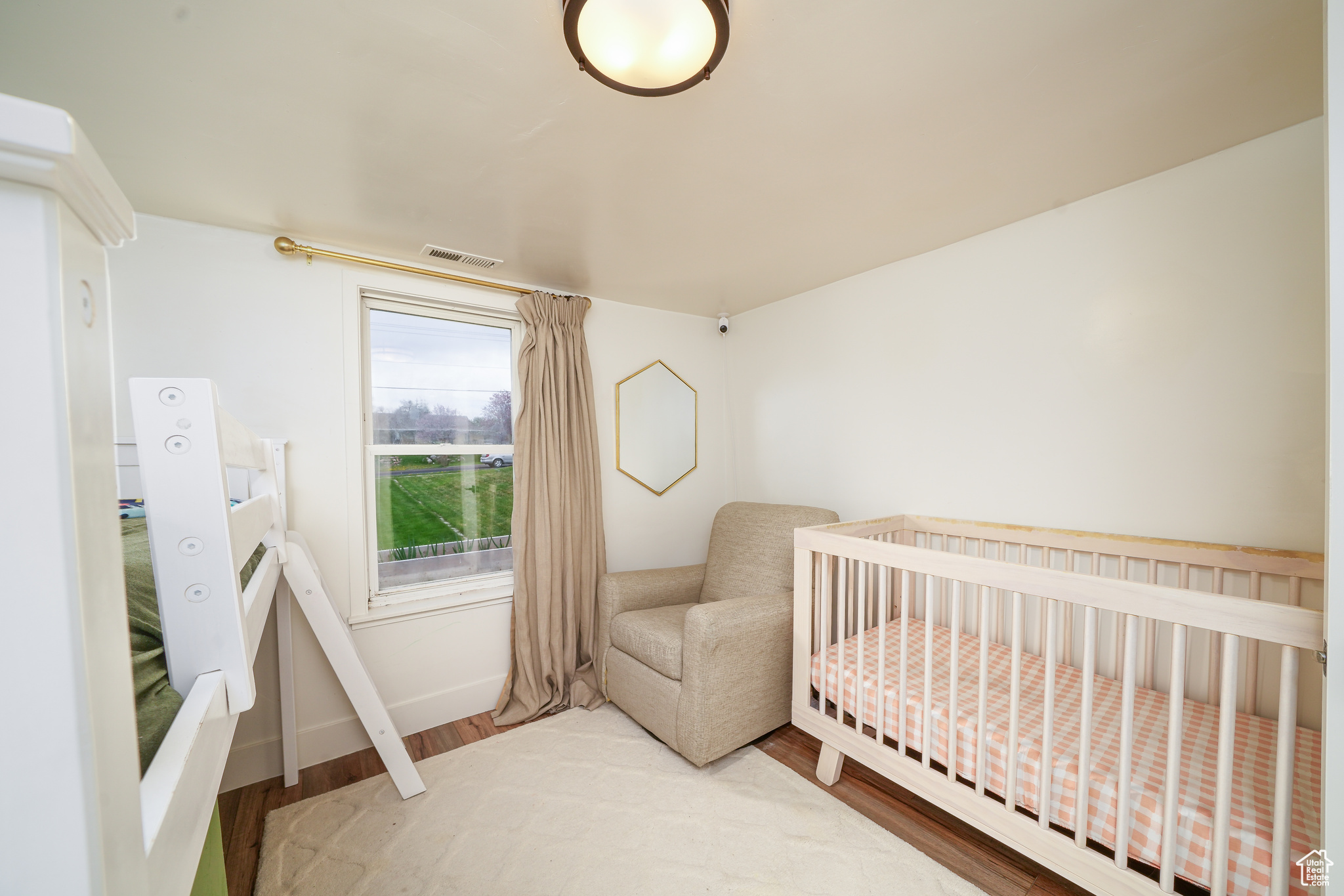 Bedroom featuring a nursery area and laminate floors