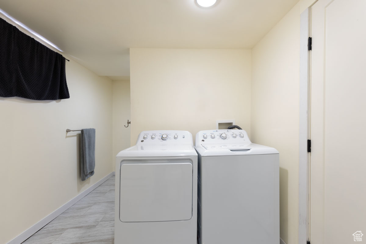 Clothes washing area with washing machine and dryer and light wood-type flooring
