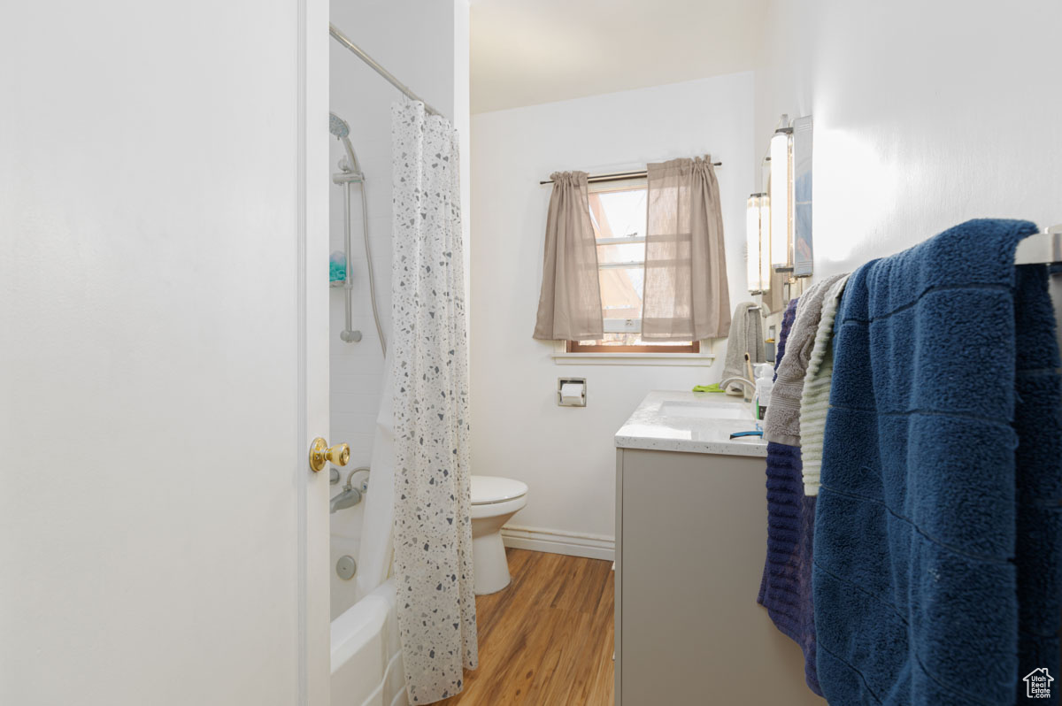 Full bathroom featuring shower / bath combo, toilet, vanity, and hardwood / wood-style floors