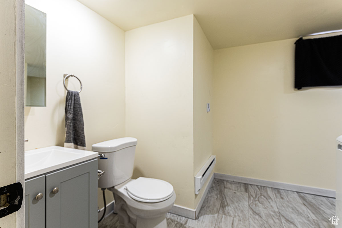 Bathroom featuring vanity, tile floors, toilet, and a baseboard heating unit