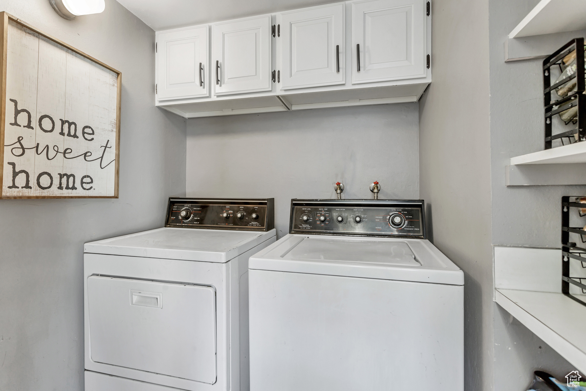 Clothes washing area with cabinets, washer hookup, and washer and clothes dryer