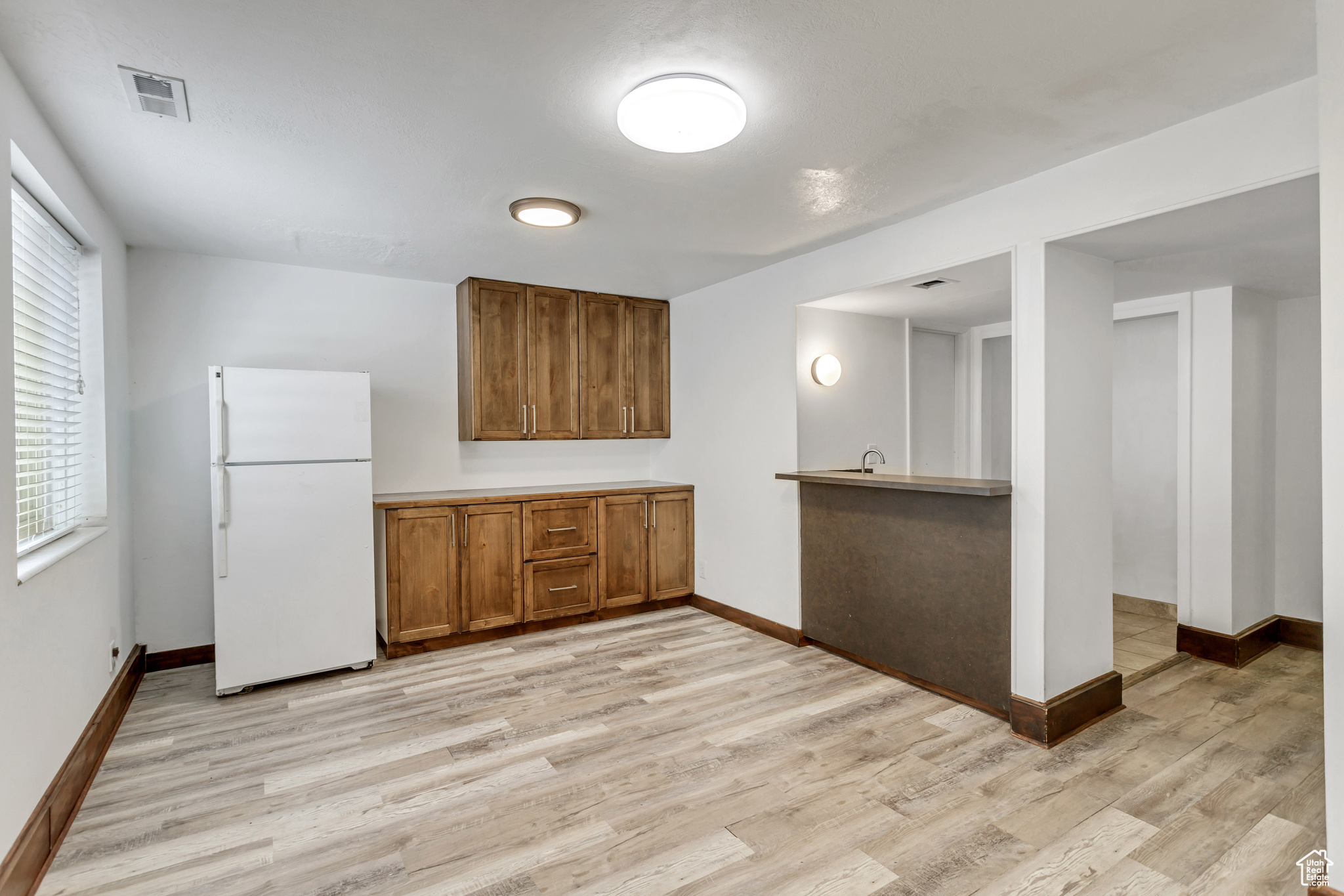 Kitchen with light hardwood / wood-style flooring, white fridge, and sink