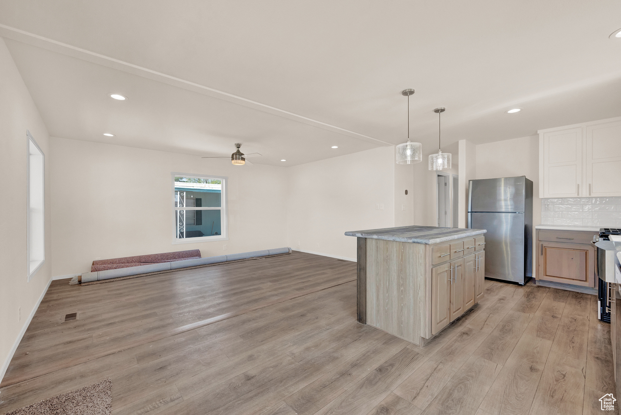 Kitchen featuring stainless steel refrigerator, a kitchen island, tasteful backsplash, light hardwood / wood-style floors, and ceiling fan