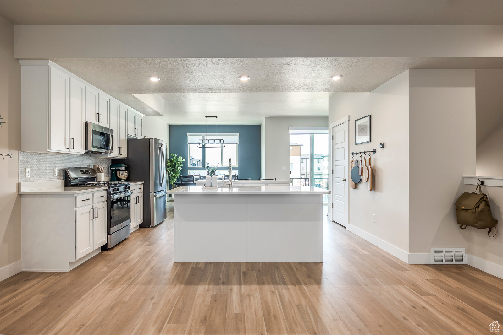 Kitchen featuring white cabinets, light wood-type flooring, and stainless steel appliances