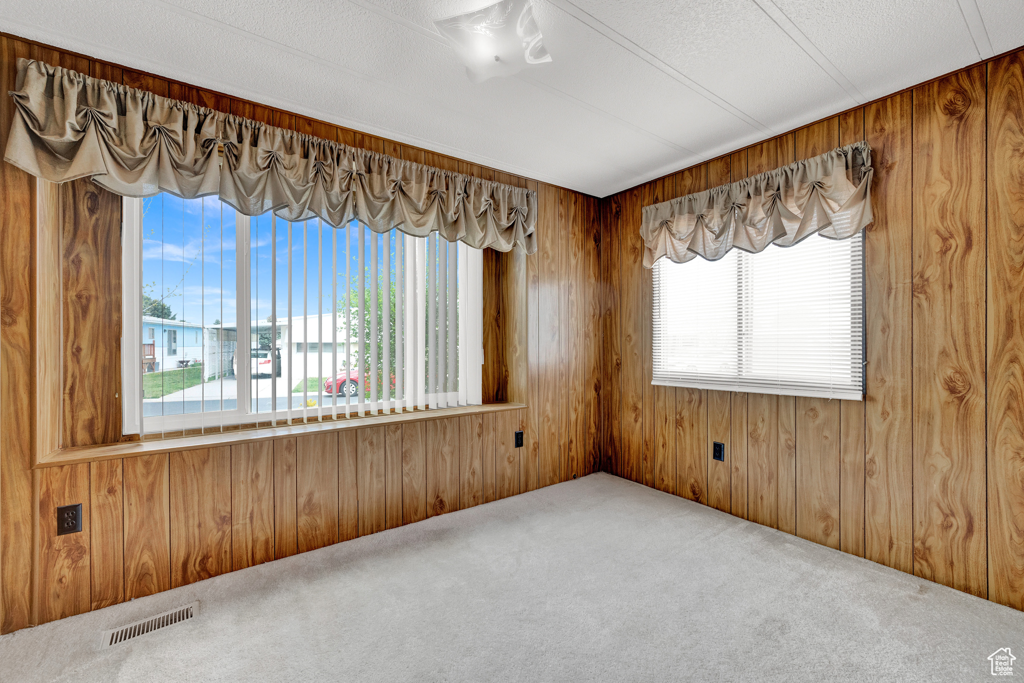 Carpeted empty room featuring wooden walls