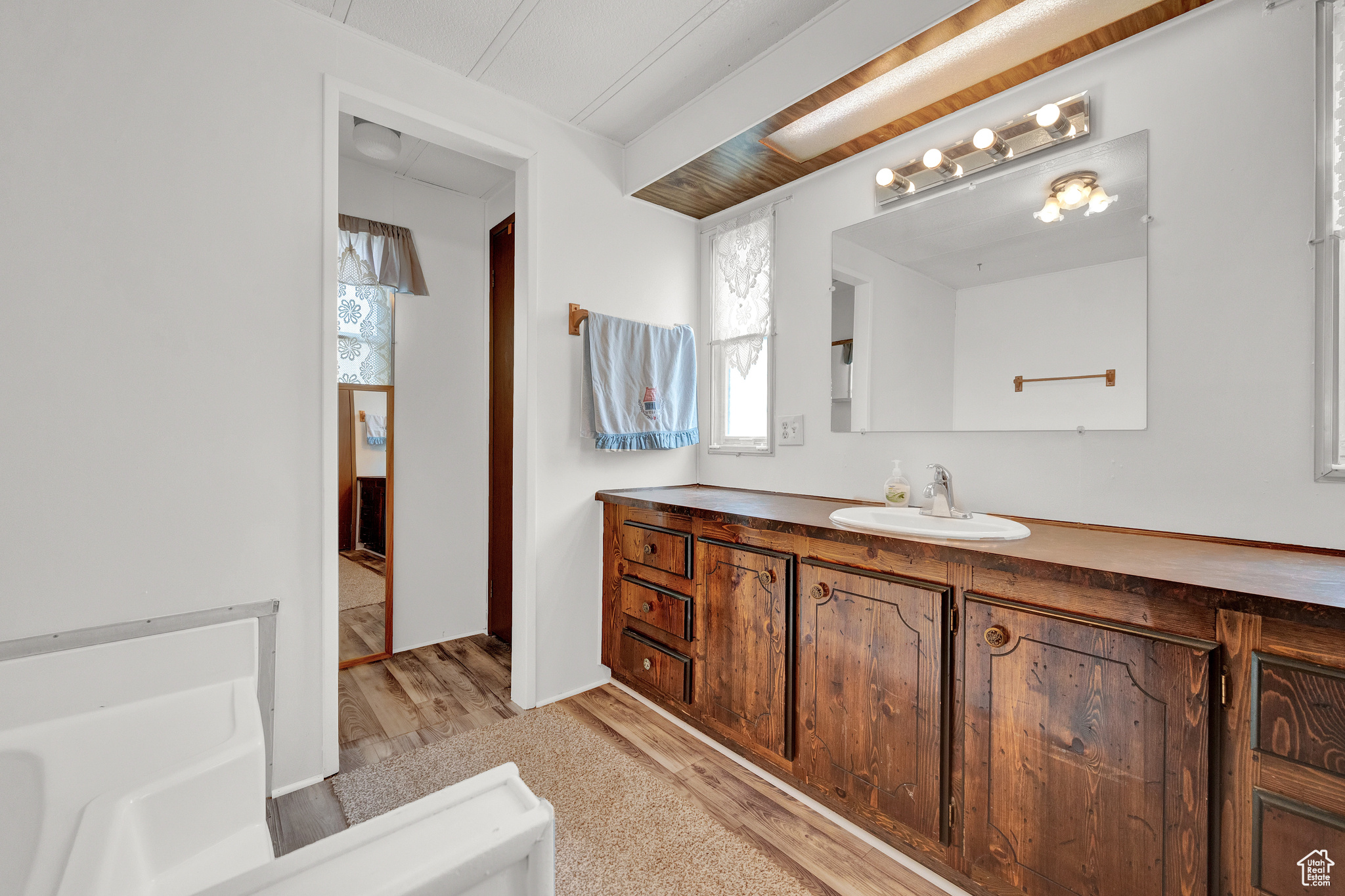 Bathroom featuring hardwood / wood-style flooring, a bathtub, and large vanity