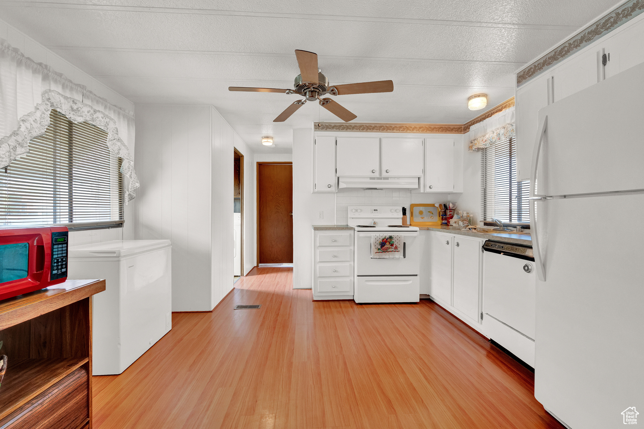 Kitchen featuring white cabinets, white appliances, light hardwood / wood-style flooring, ceiling fan, and a textured ceiling
