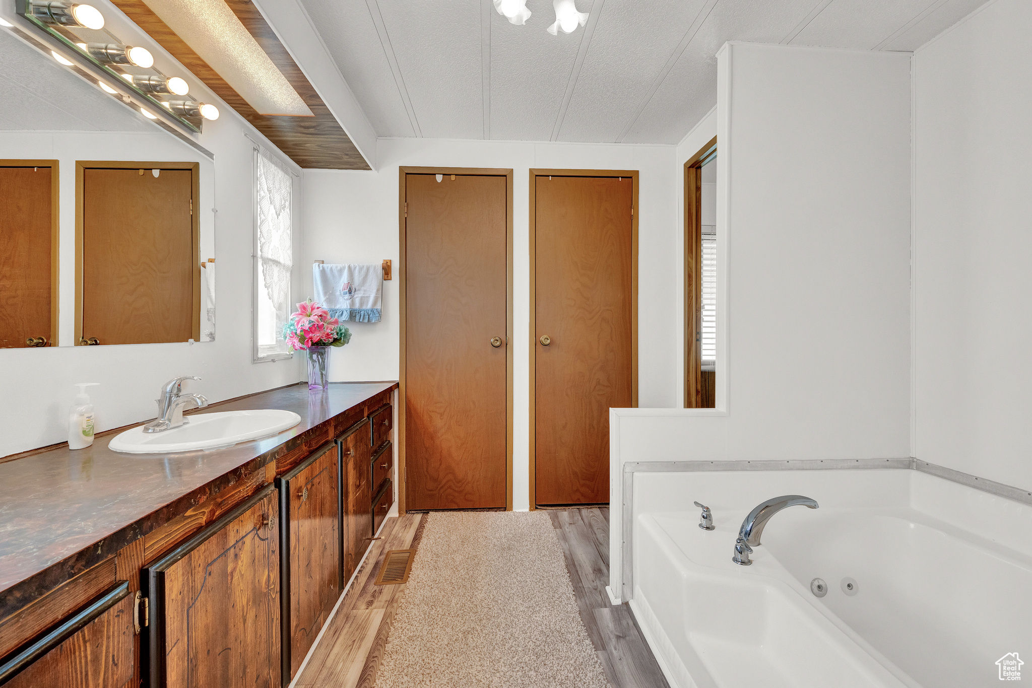 Bathroom with hardwood / wood-style flooring, oversized vanity, and a tub