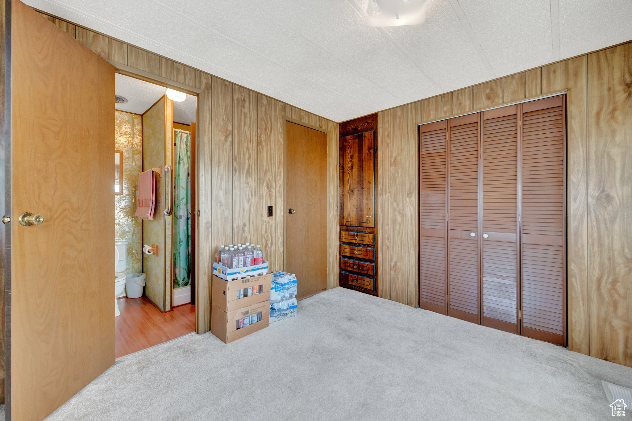 Bedroom with a closet, carpet flooring, and wooden walls