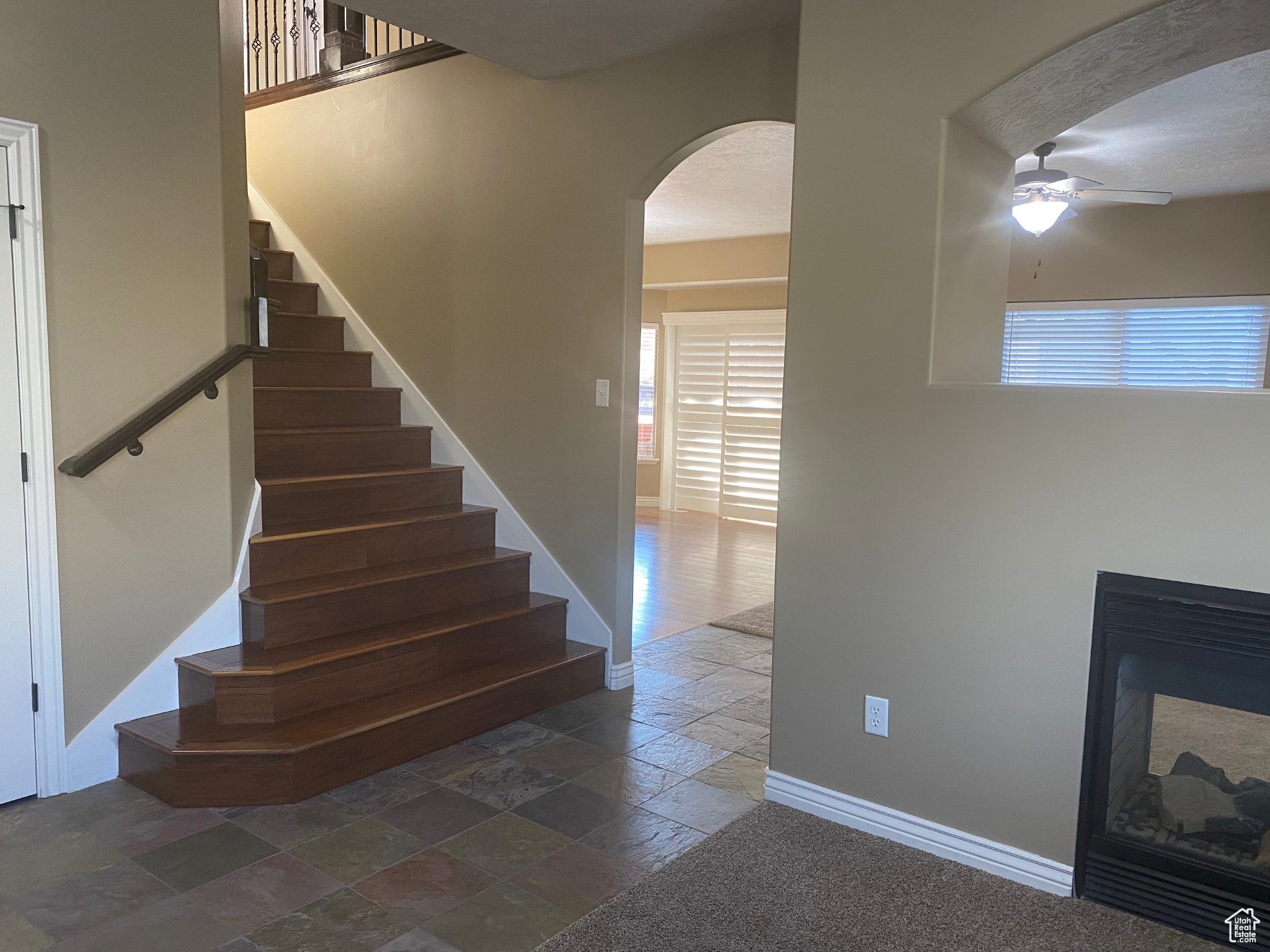 Staircase featuring ceiling fan and dark tile floors