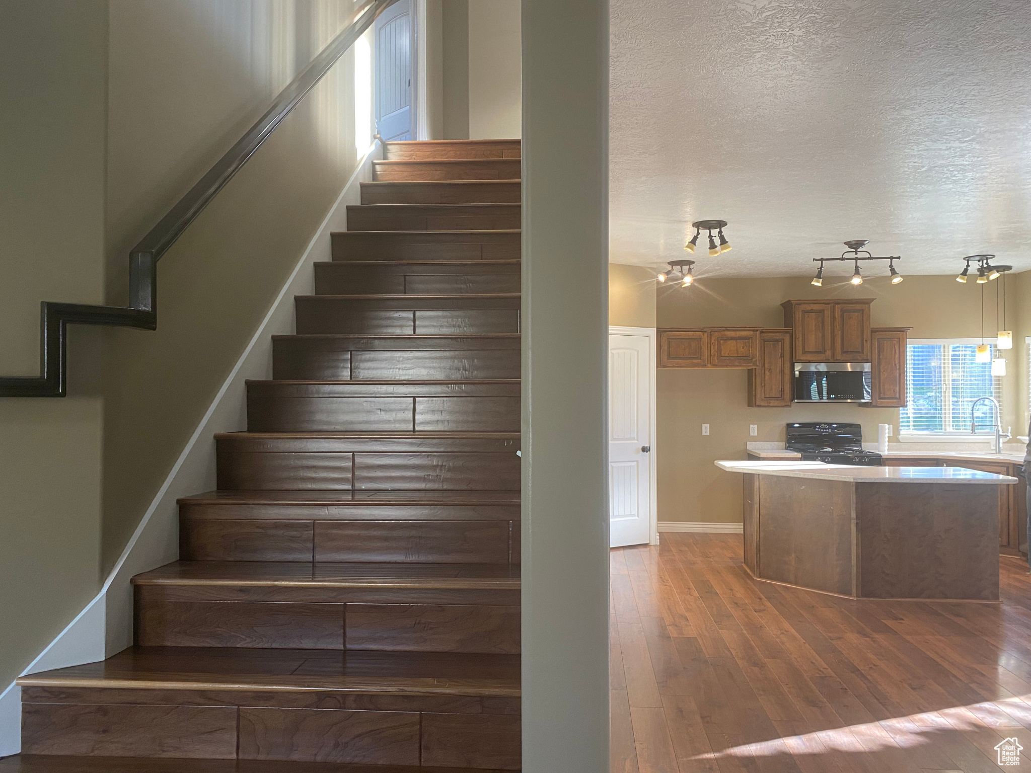 Stairs featuring rail lighting, dark hardwood / wood-style floors, and a textured ceiling