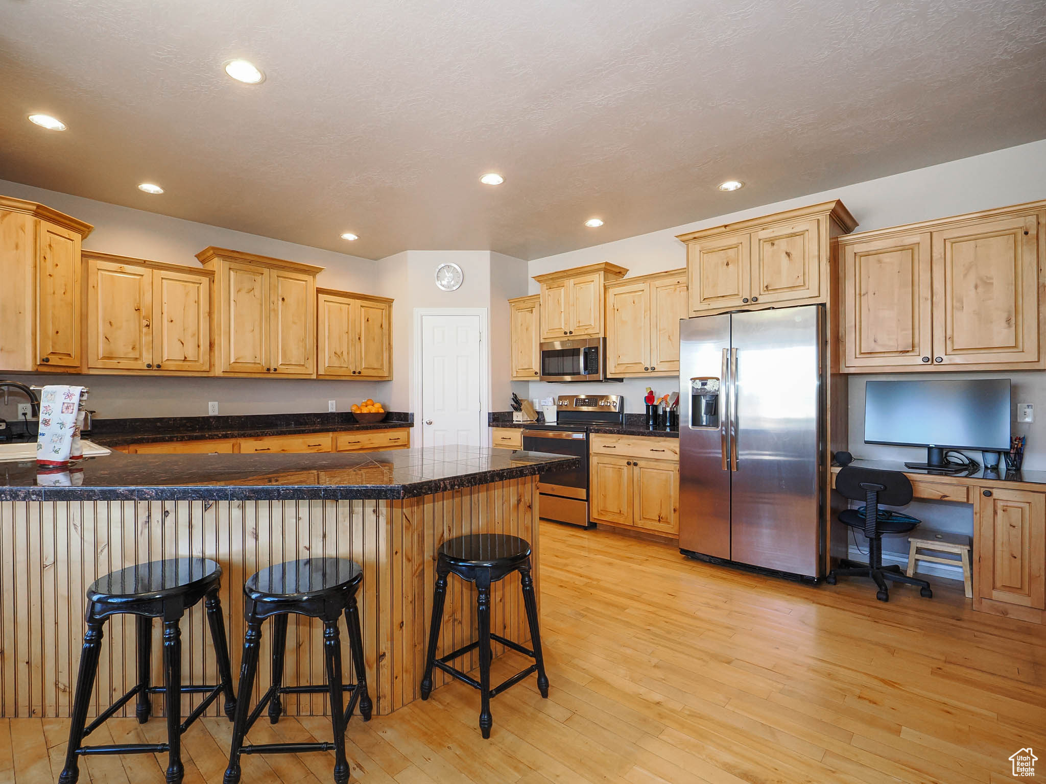 Kitchen with appliances with stainless steel finishes, light hardwood flooring, a breakfast bar area