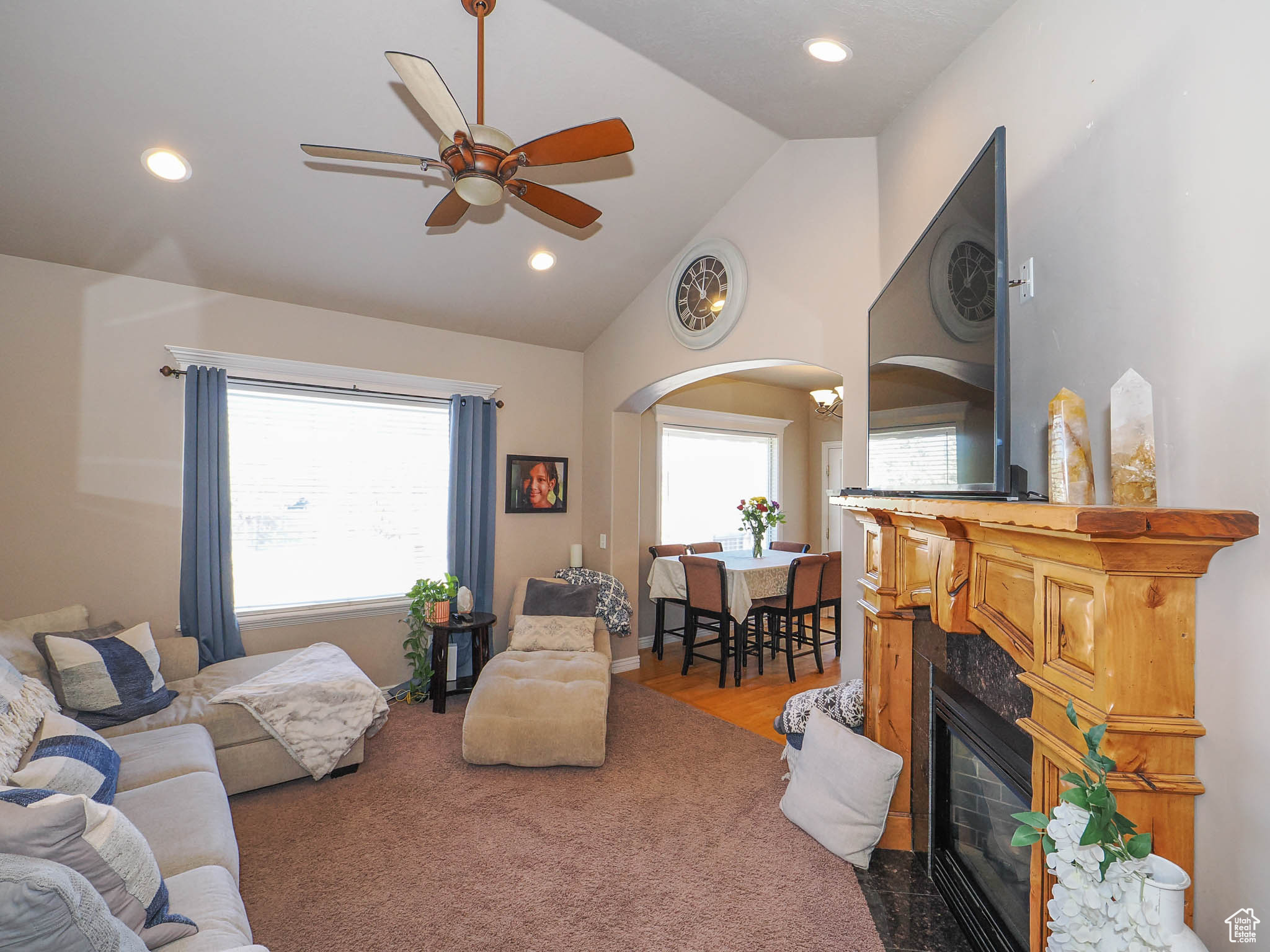 Family room featuring high vaulted ceiling, ceiling fan, carpet floors, and a fireplace
