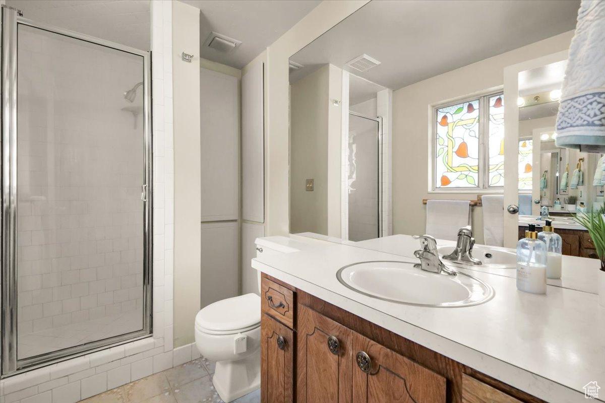 Bathroom with an enclosed shower, tile floors, toilet, and vanity with extensive cabinet space. Real Stained Glass.