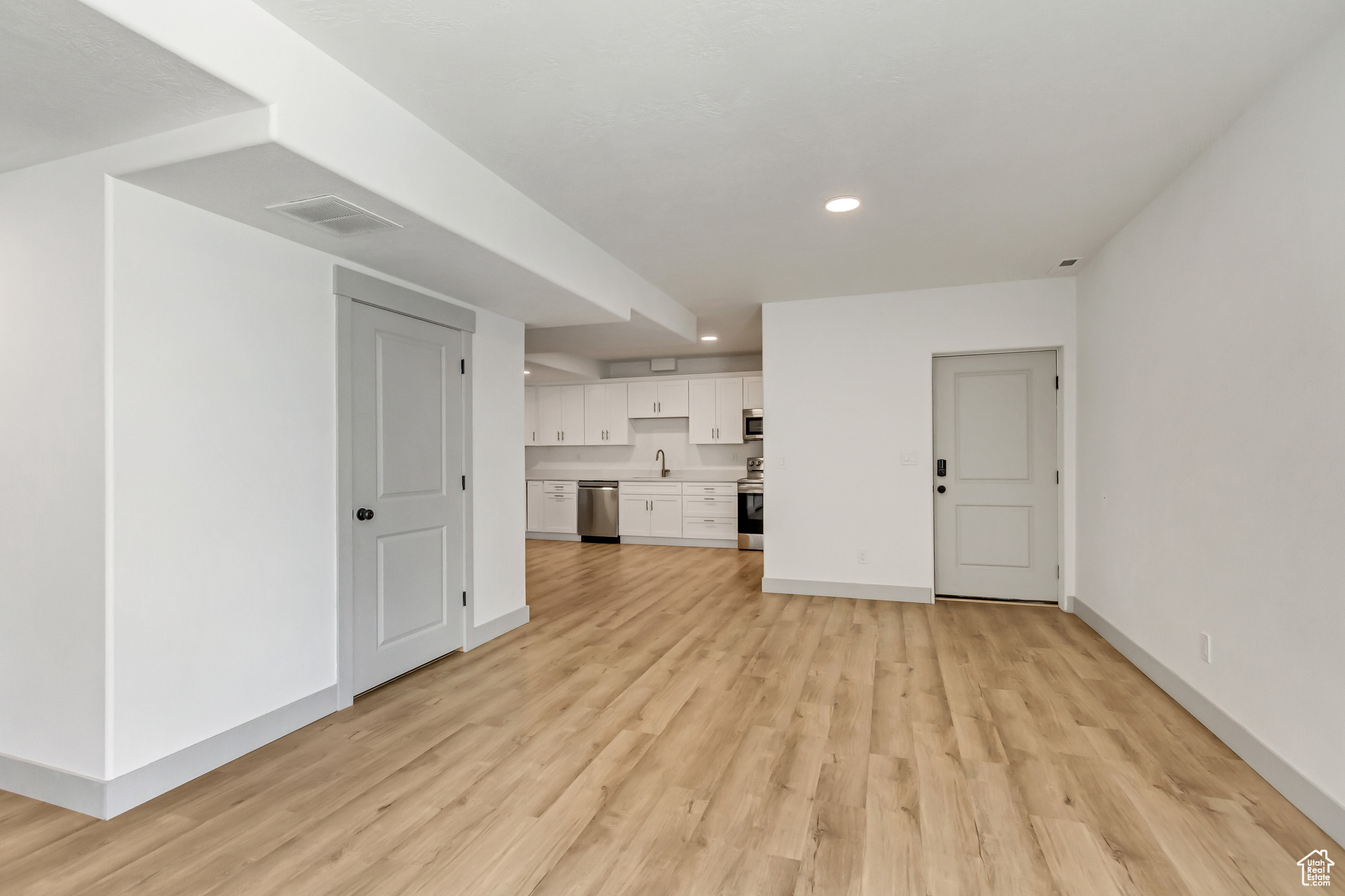 Basement with sink and light hardwood / wood-style flooring