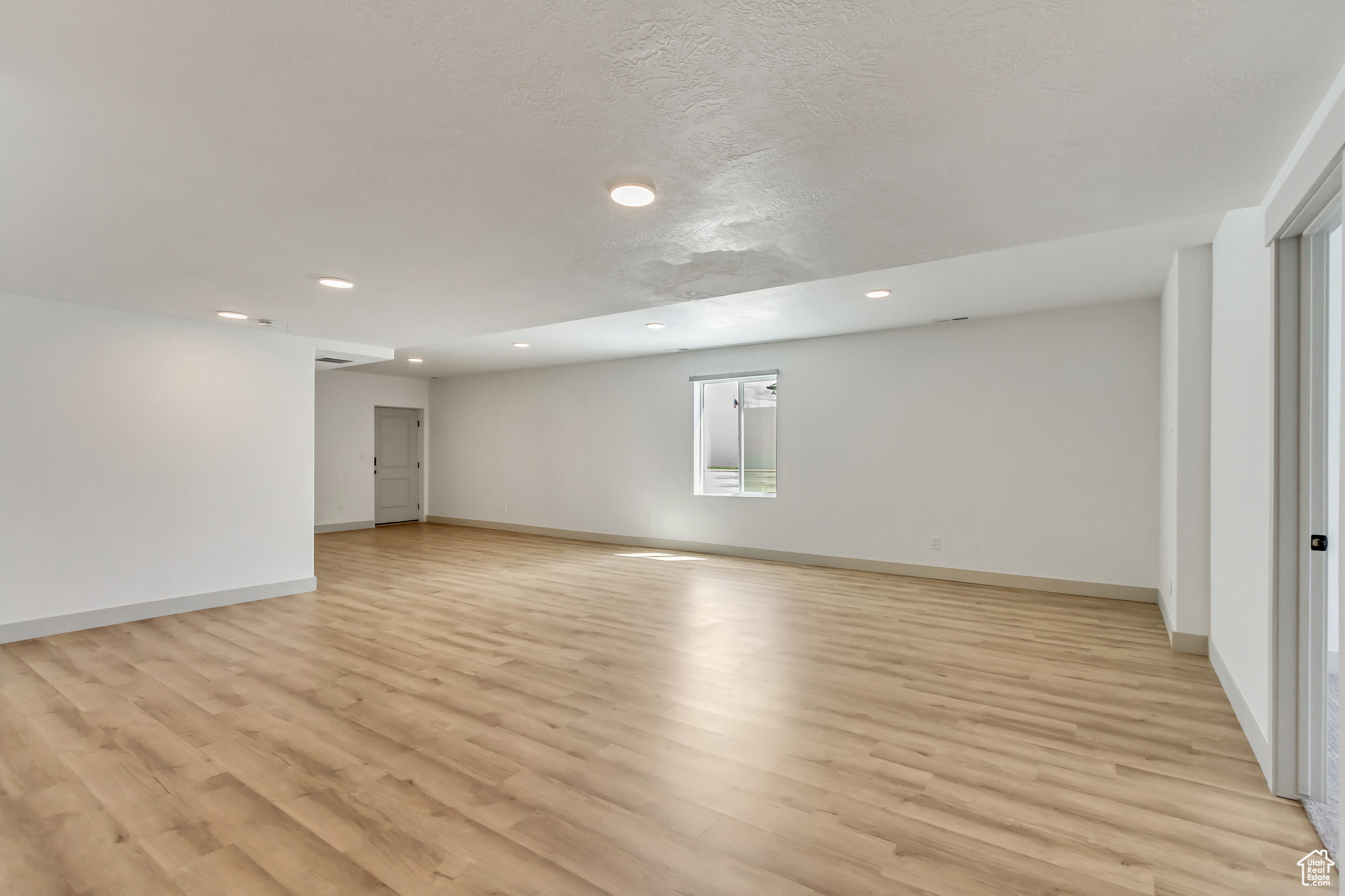Unfurnished room featuring light wood-type flooring and a textured ceiling