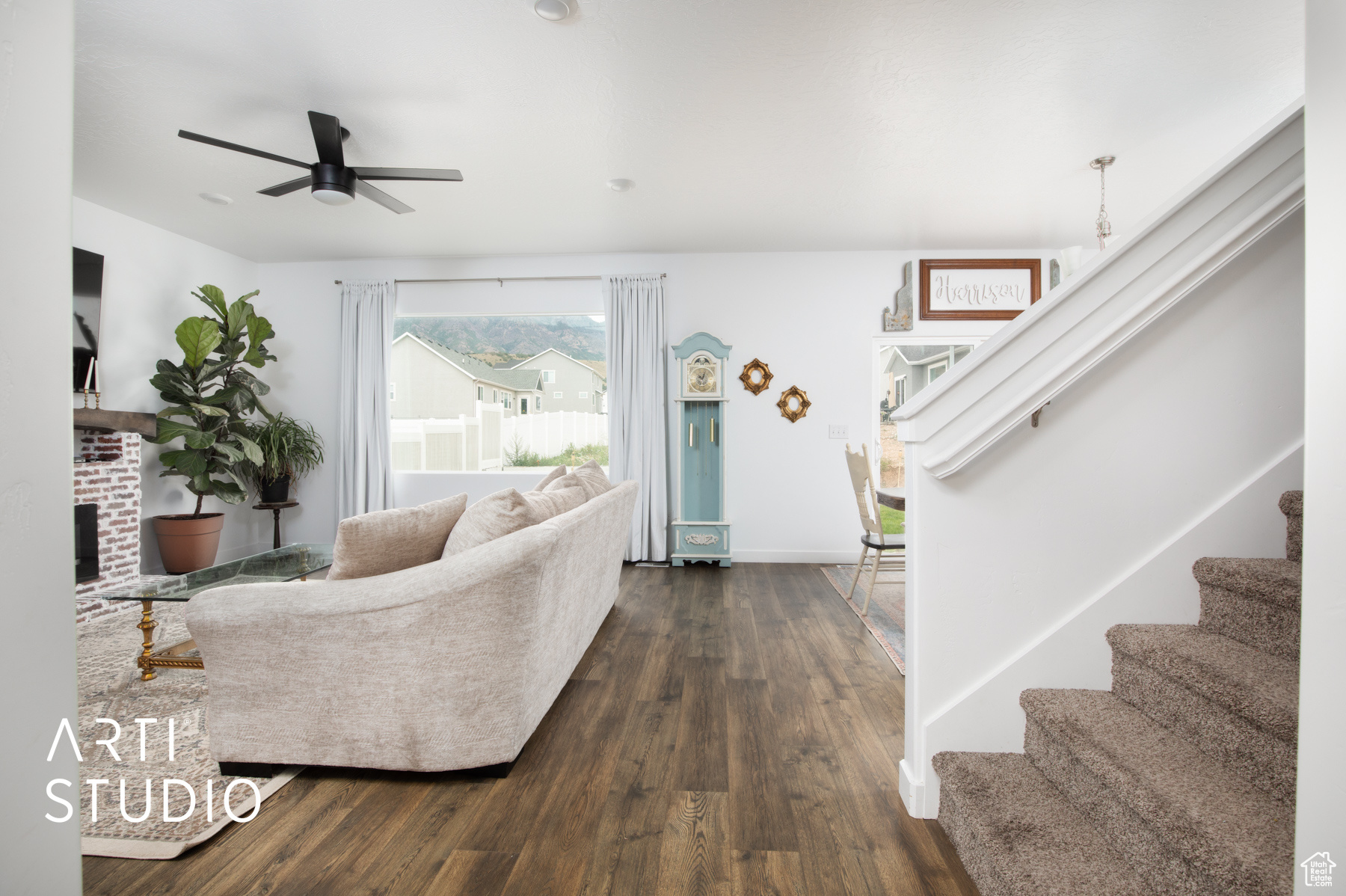 Living room featuring dark wood-type flooring, a brick fireplace, and ceiling fan