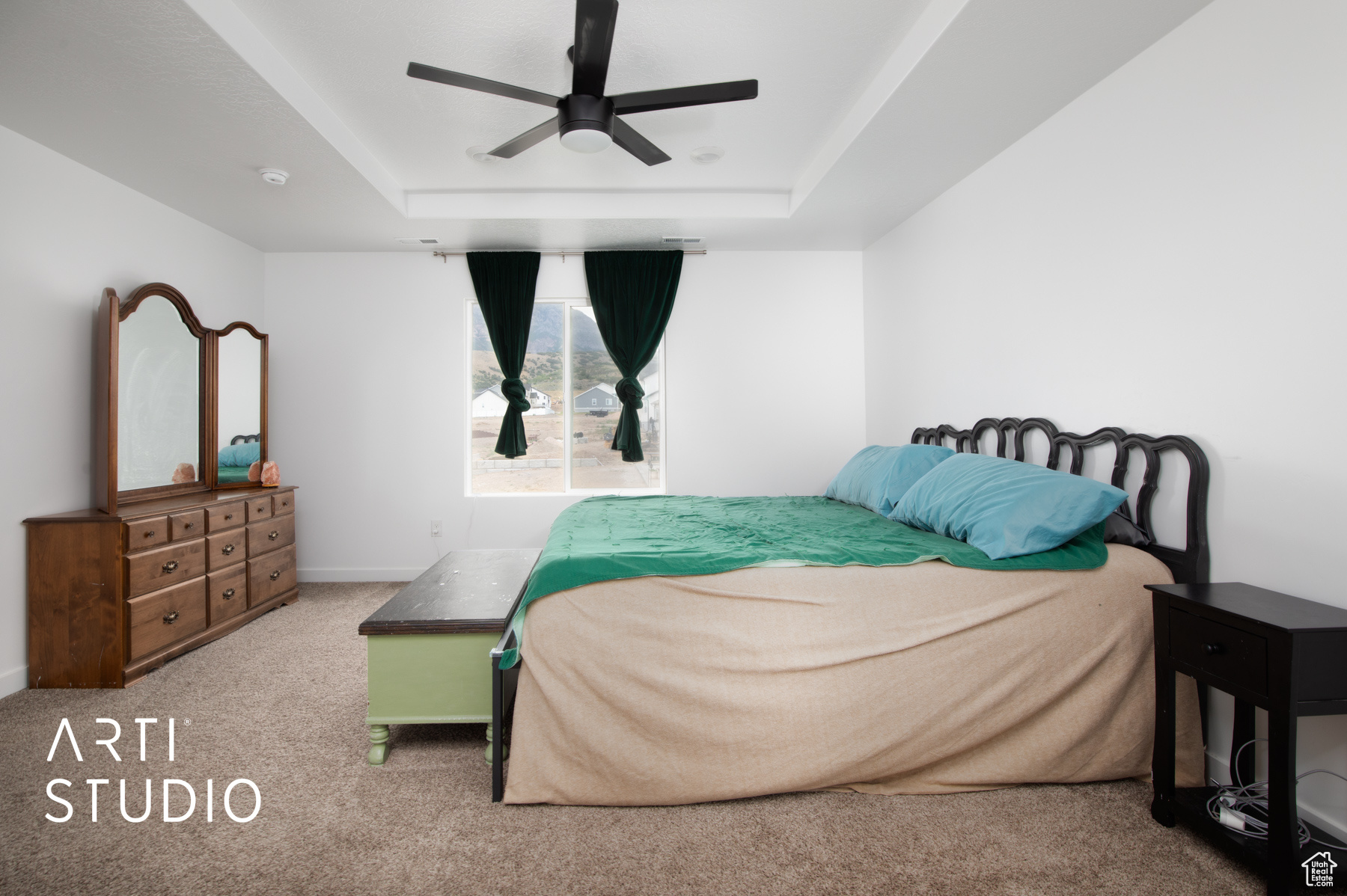 Carpeted bedroom featuring ceiling fan and a tray ceiling